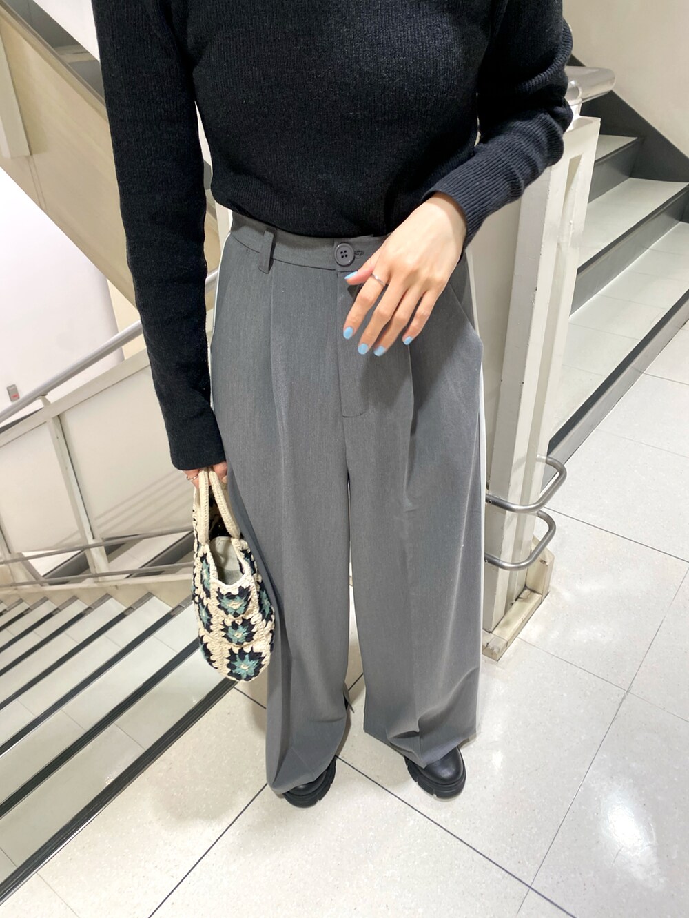 ブラック系のニット/セーター、グレー系のスラックスを着用したレディースの春コーディネートの2枚目の写真