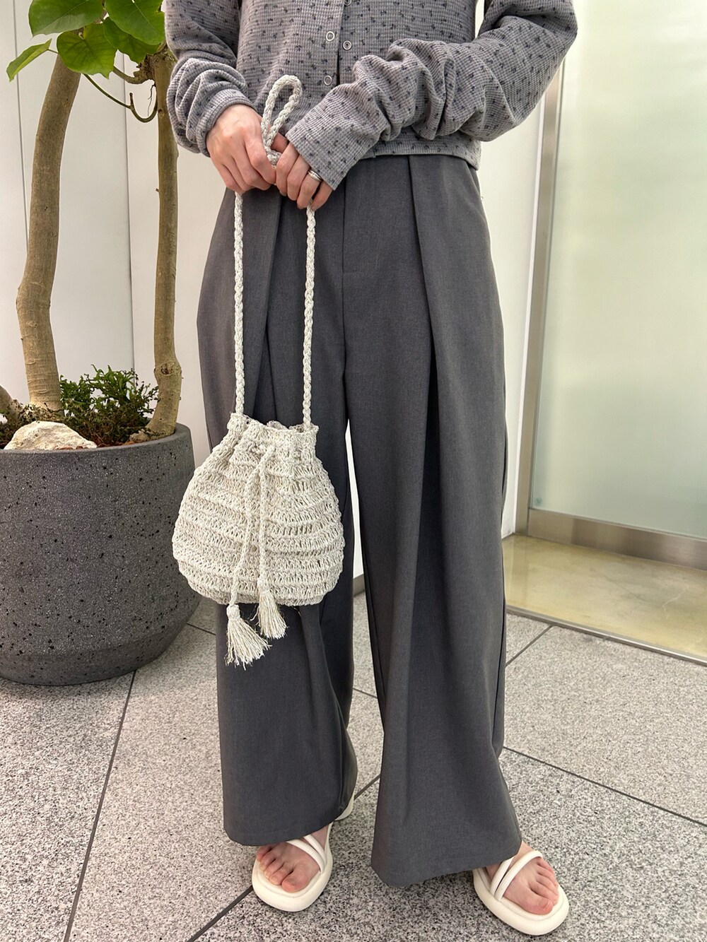 グレー系のカーディガン/ボレロ、グレー系のスラックス、ブラック系のサンダルを着用したレディースの春コーディネートの5枚目の写真