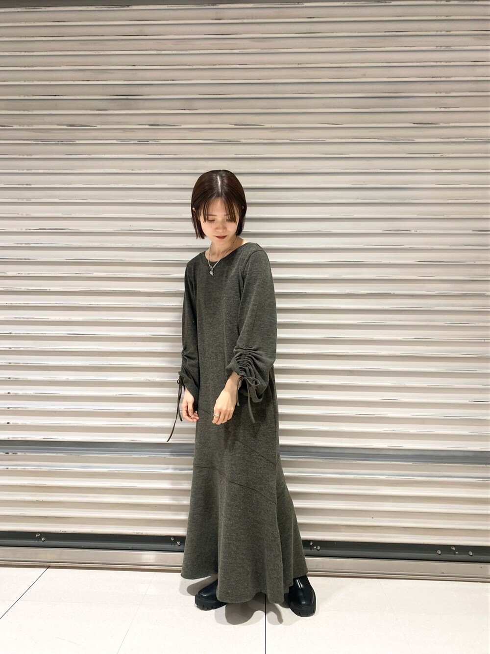 ブラック系のブーツ、グリーン系のワンピース、ホワイト系のベストを着用したレディースの冬コーディネートの2枚目の写真