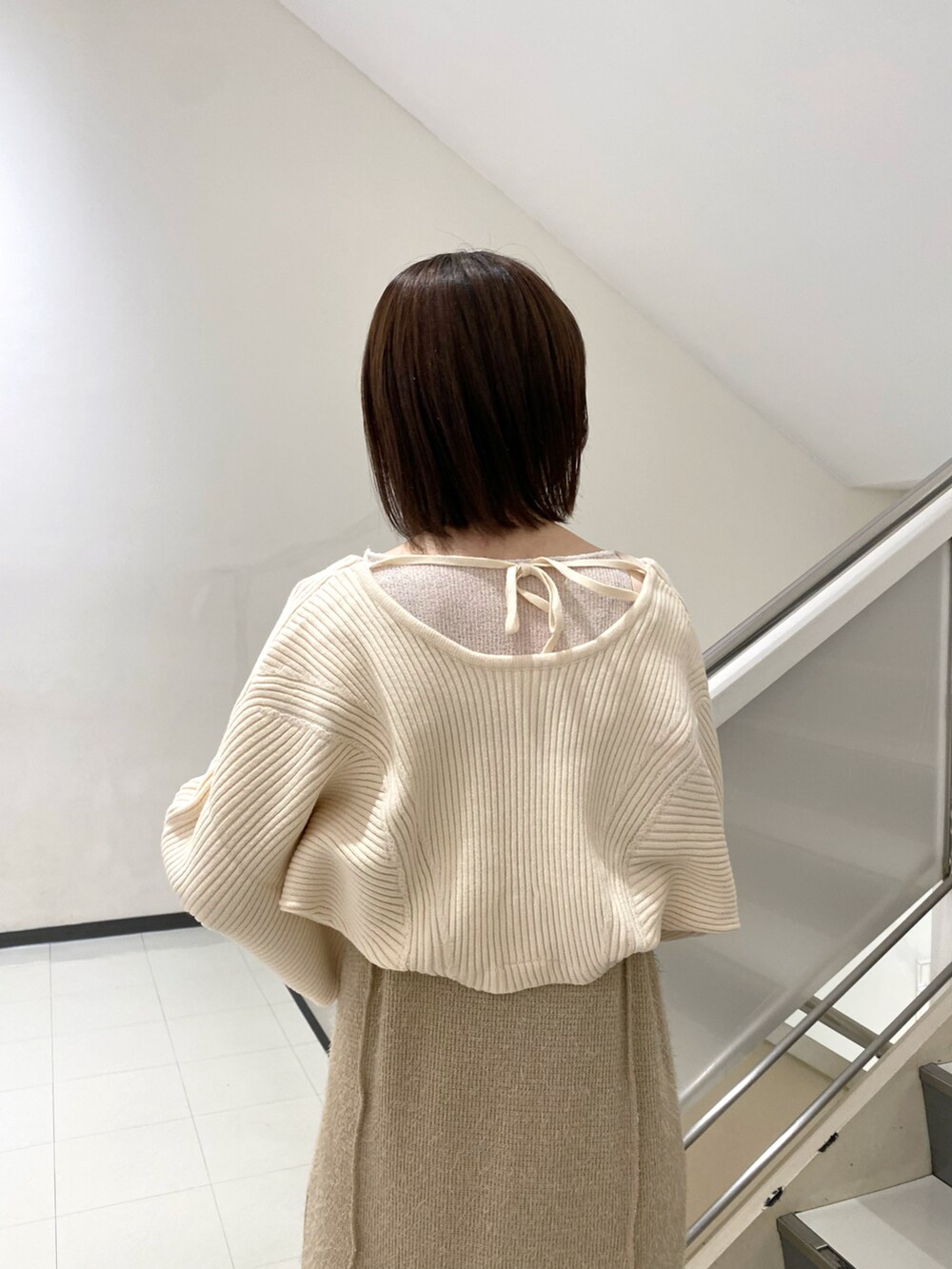 ホワイト系のカーディガン/ボレロ、ベージュ系のワンピース、ブラック系のブーツを着用したレディースの冬コーディネートの4枚目の写真