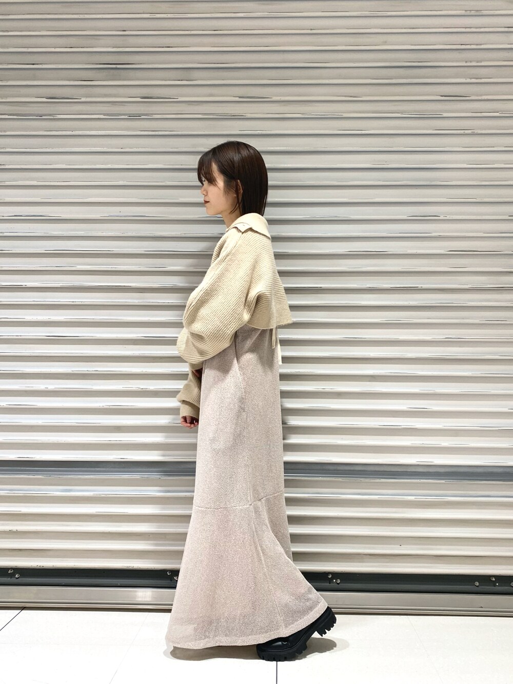 ホワイト系のニット/セーター、ベージュ系のワンピース、ブラック系のブーツを着用したレディースの冬コーディネートの2枚目の写真