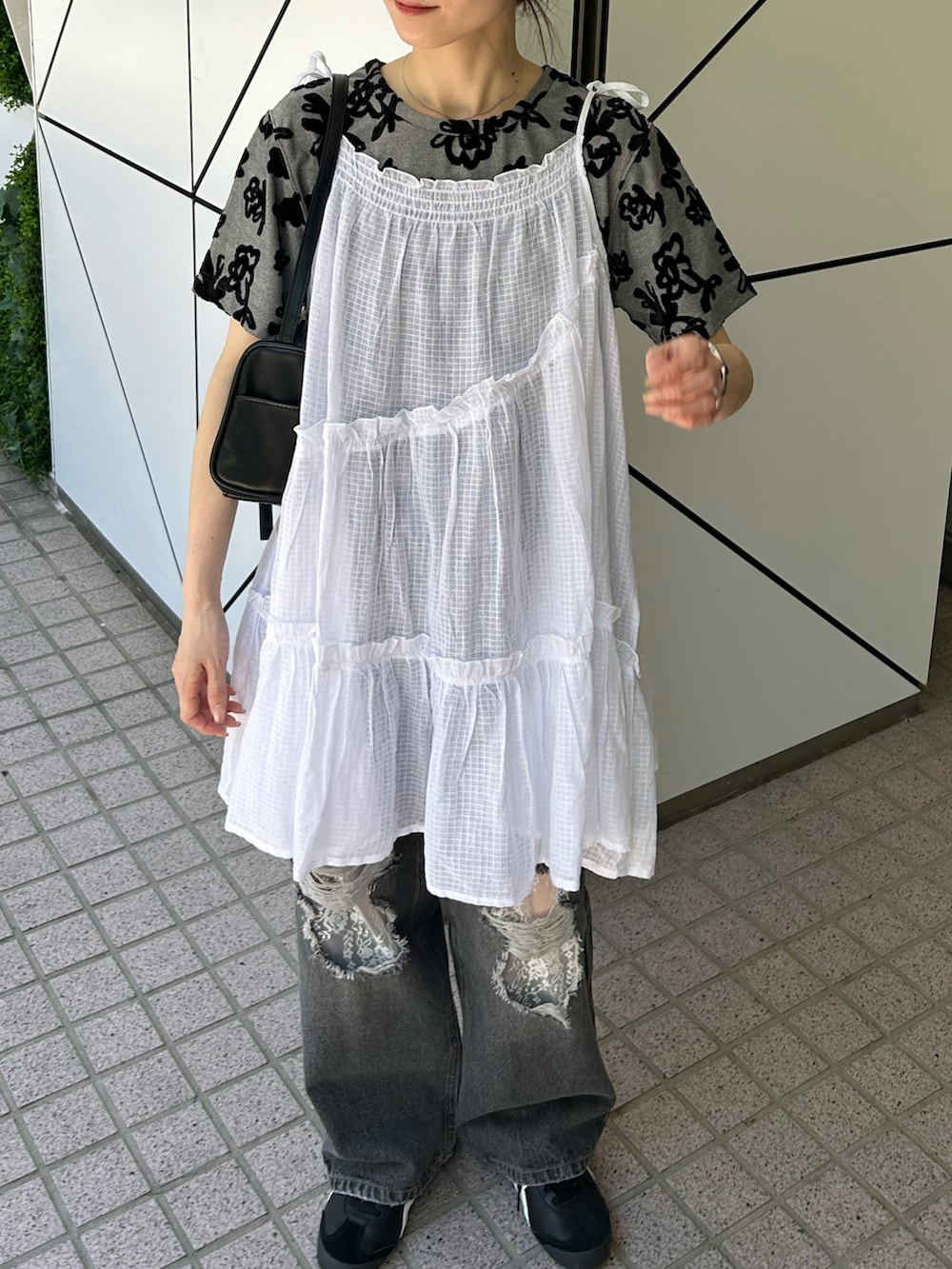 ホワイト系のチュニック、ブラック系のデニムパンツ、ブラック系のショルダーバッグを着用したレディースの夏コーディネートの2枚目の写真