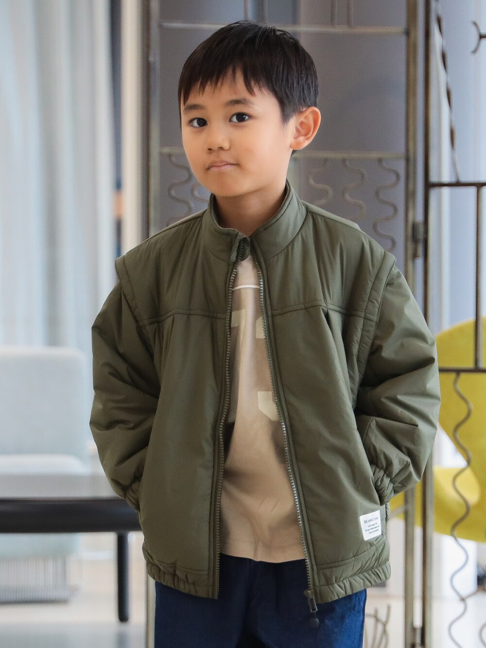 グリーン系のブルゾン、ブルー系のその他パンツ、ベージュ系のTシャツ/カットソーを着用したキッズの秋コーディネートの2枚目の写真
