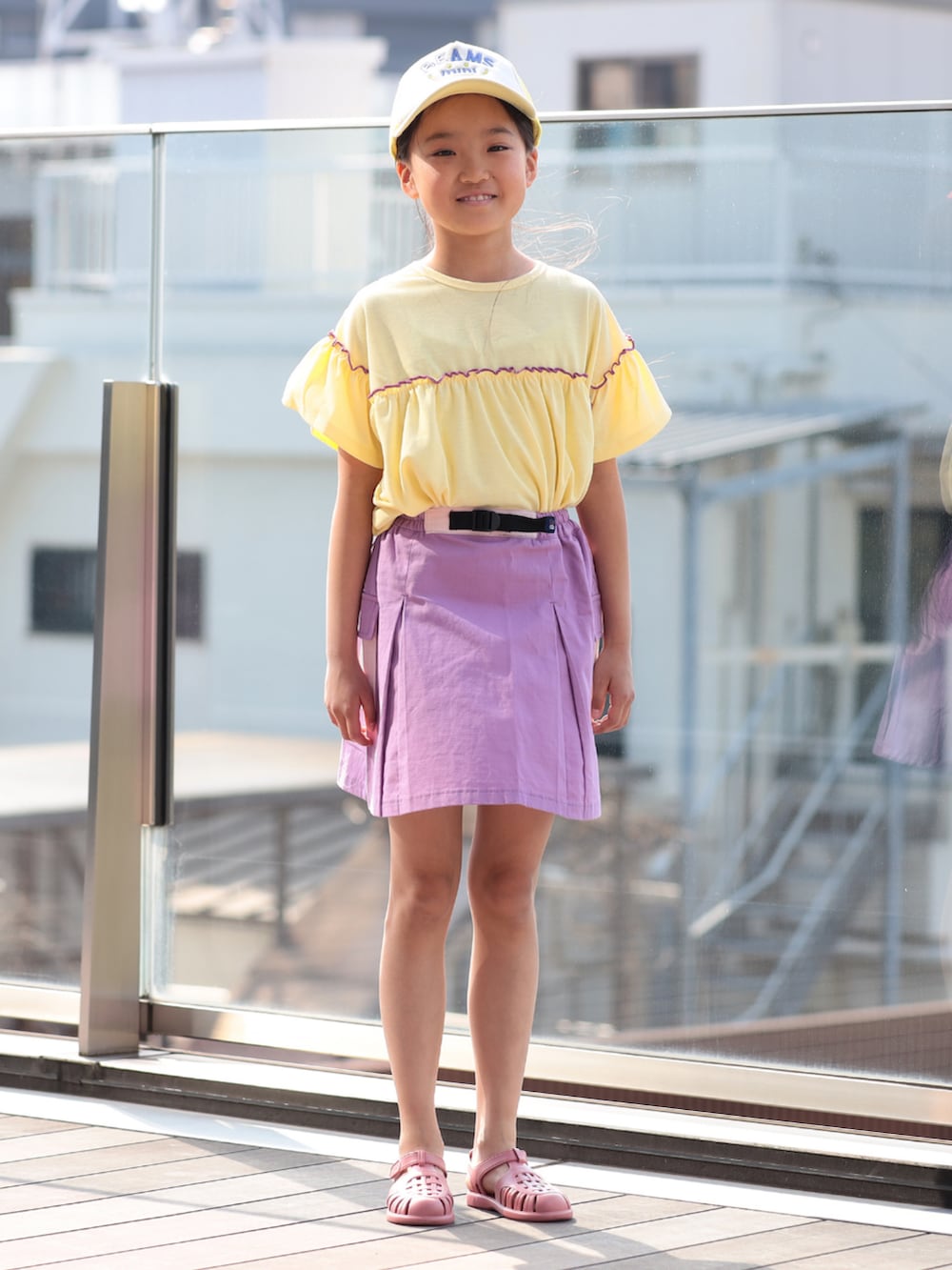 イエロー系のTシャツ/カットソー、パープル系のスカート、イエロー系のキャップを着用したキッズの夏コーディネートの2枚目の写真