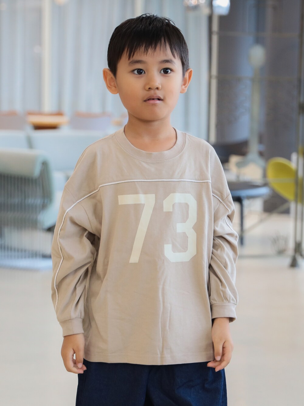 グリーン系のブルゾン、ブルー系のその他パンツ、ベージュ系のTシャツ/カットソーを着用したキッズの秋コーディネートの6枚目の写真