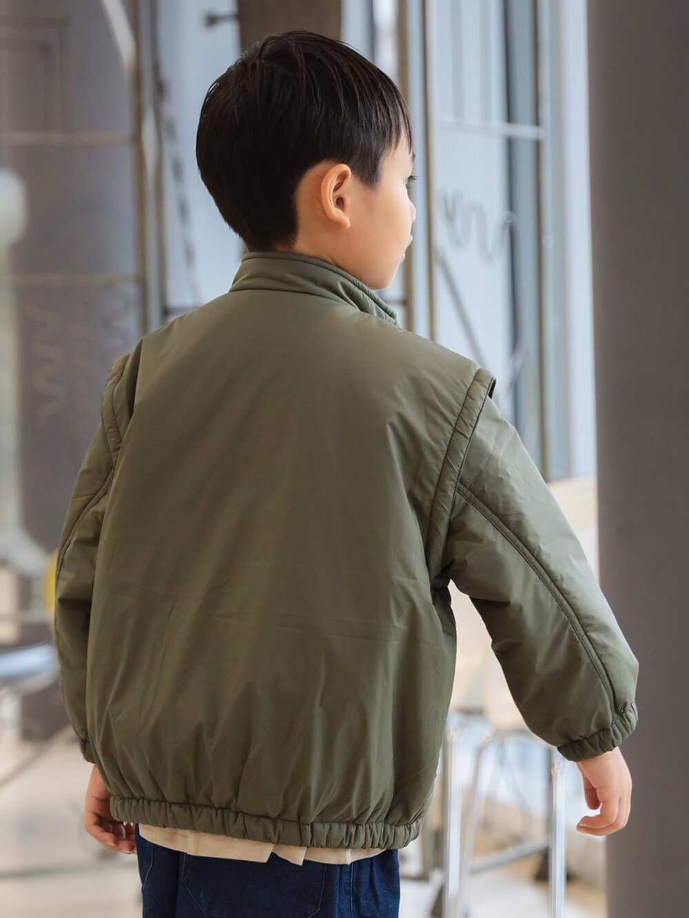 グリーン系のブルゾン、ブルー系のその他パンツ、ベージュ系のTシャツ/カットソーを着用したキッズの秋コーディネートの3枚目の写真