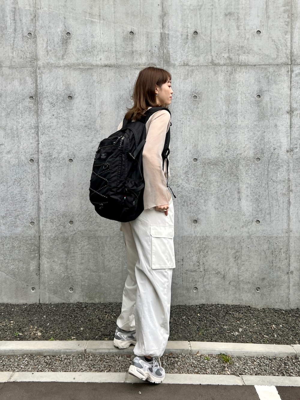 ホワイト系のカーゴパンツ、ベージュ系のTシャツ/カットソー、ブラック系のバックパック/リュックを着用したレディースの春コーディネートの2枚目の写真