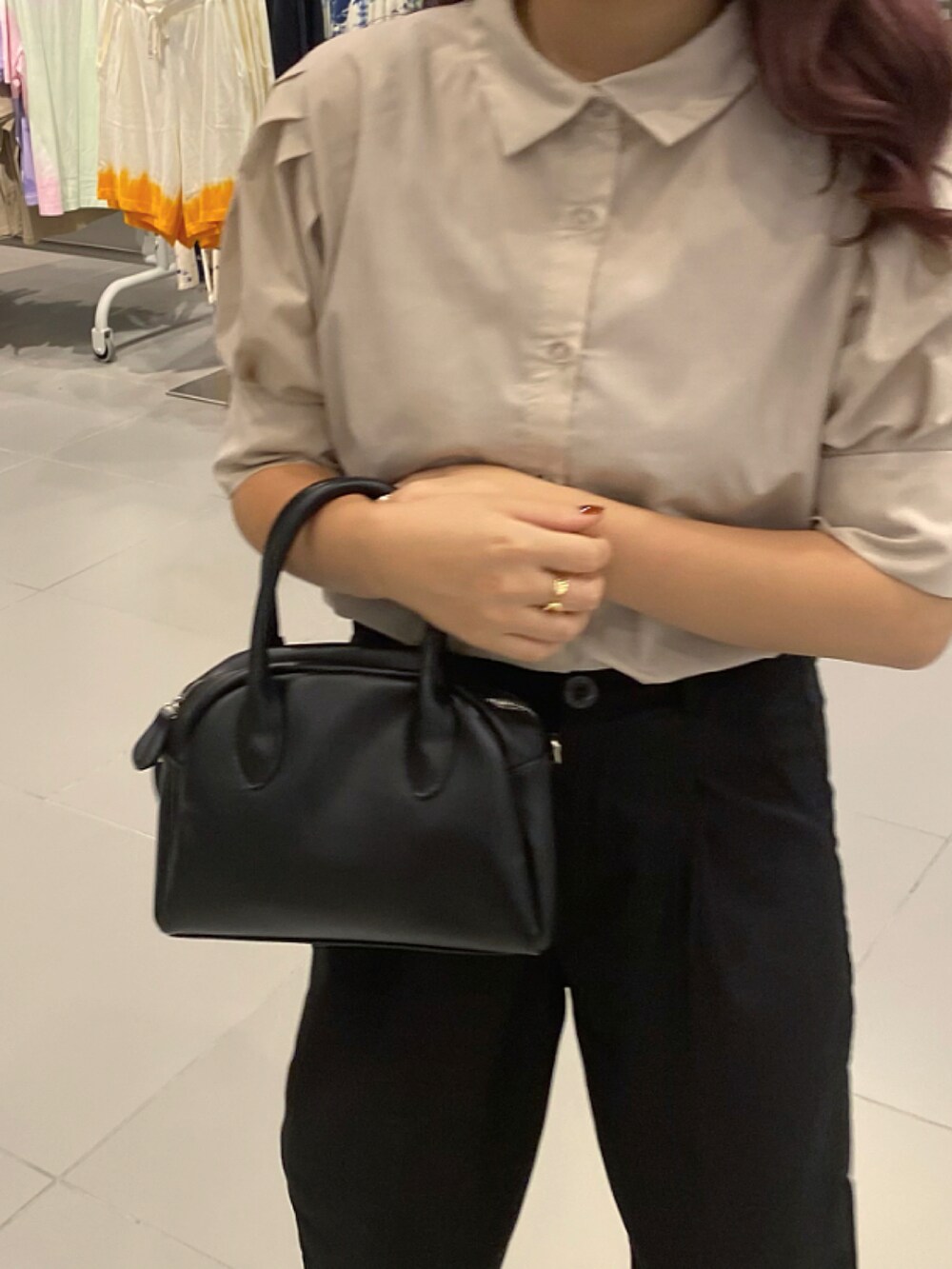 ブラック系のショルダーバッグ、ベージュ系のトップス、ブラック系のスラックスを着用したレディースの夏コーディネートの3枚目の写真