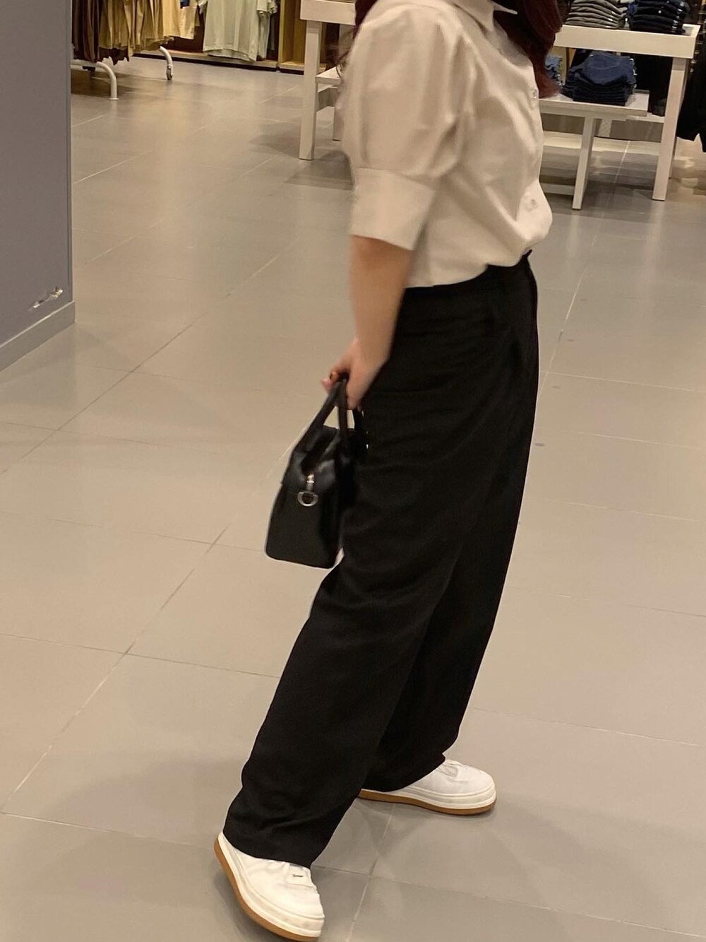 ブラック系のショルダーバッグ、ベージュ系のトップス、ブラック系のスラックスを着用したレディースの夏コーディネートの2枚目の写真