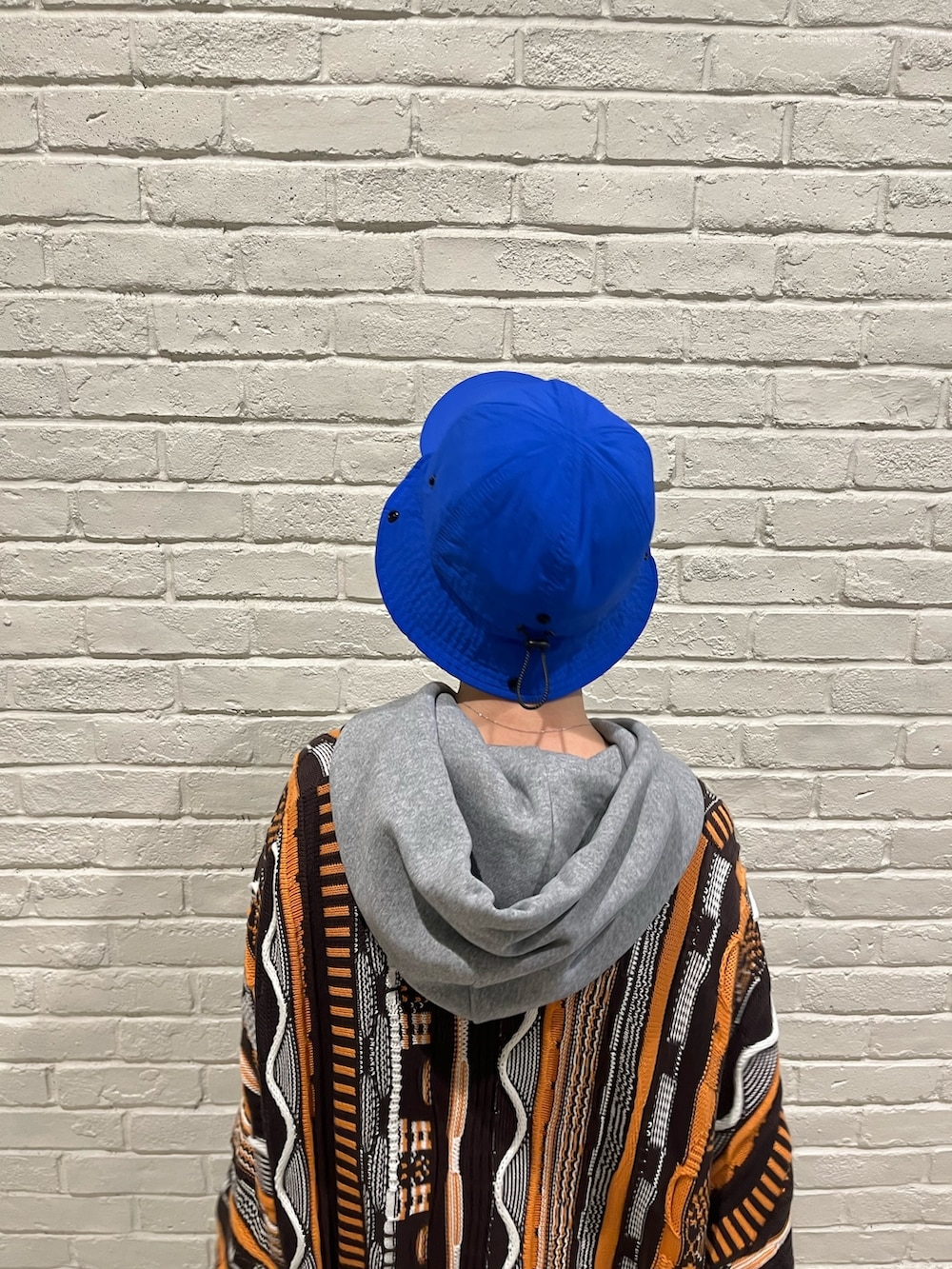 ベージュ系のパンツ、ブラック系のスニーカー、ブルー系のキャップを着用したレディースの春コーディネートの4枚目の写真