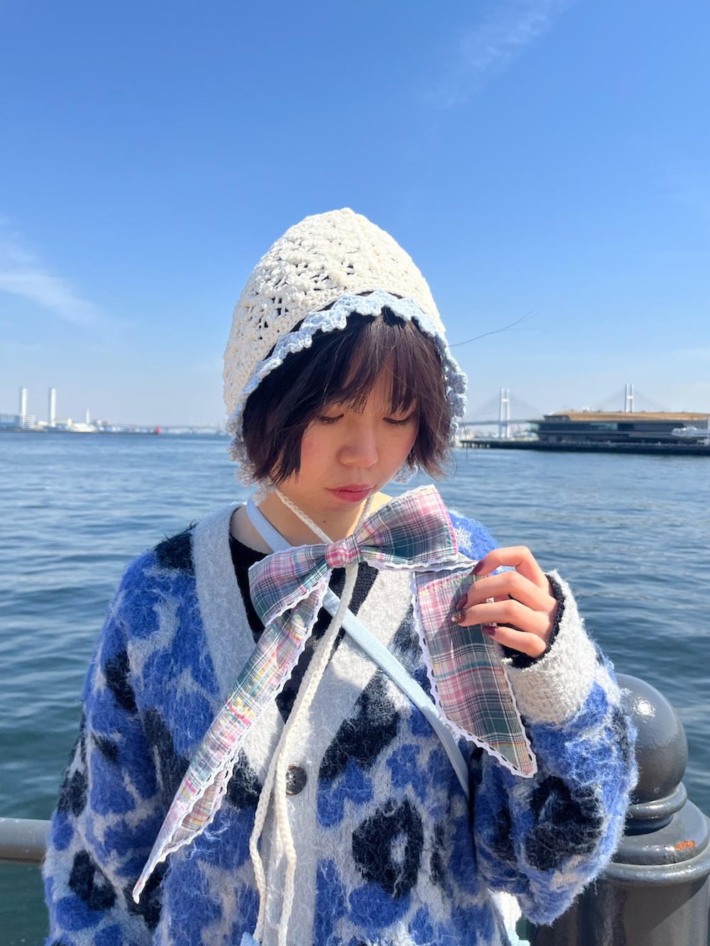 ブルー系のトートバッグ、ホワイト系のハット、グリーン系のシュシュを着用したレディースの春コーディネートの2枚目の写真