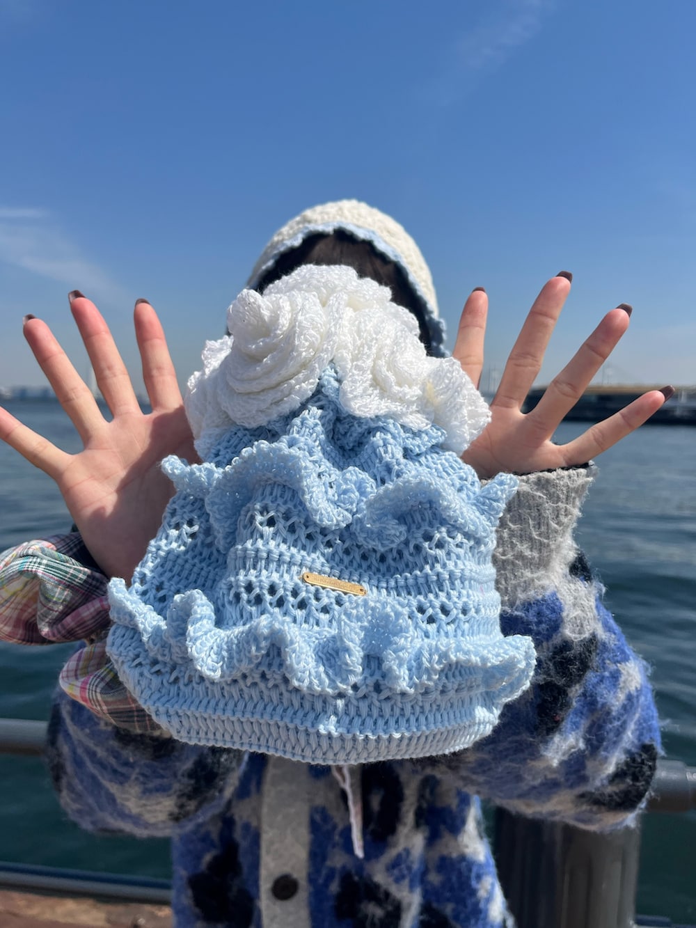 ブルー系のトートバッグ、ホワイト系のハット、グリーン系のシュシュを着用したレディースの春コーディネートの3枚目の写真