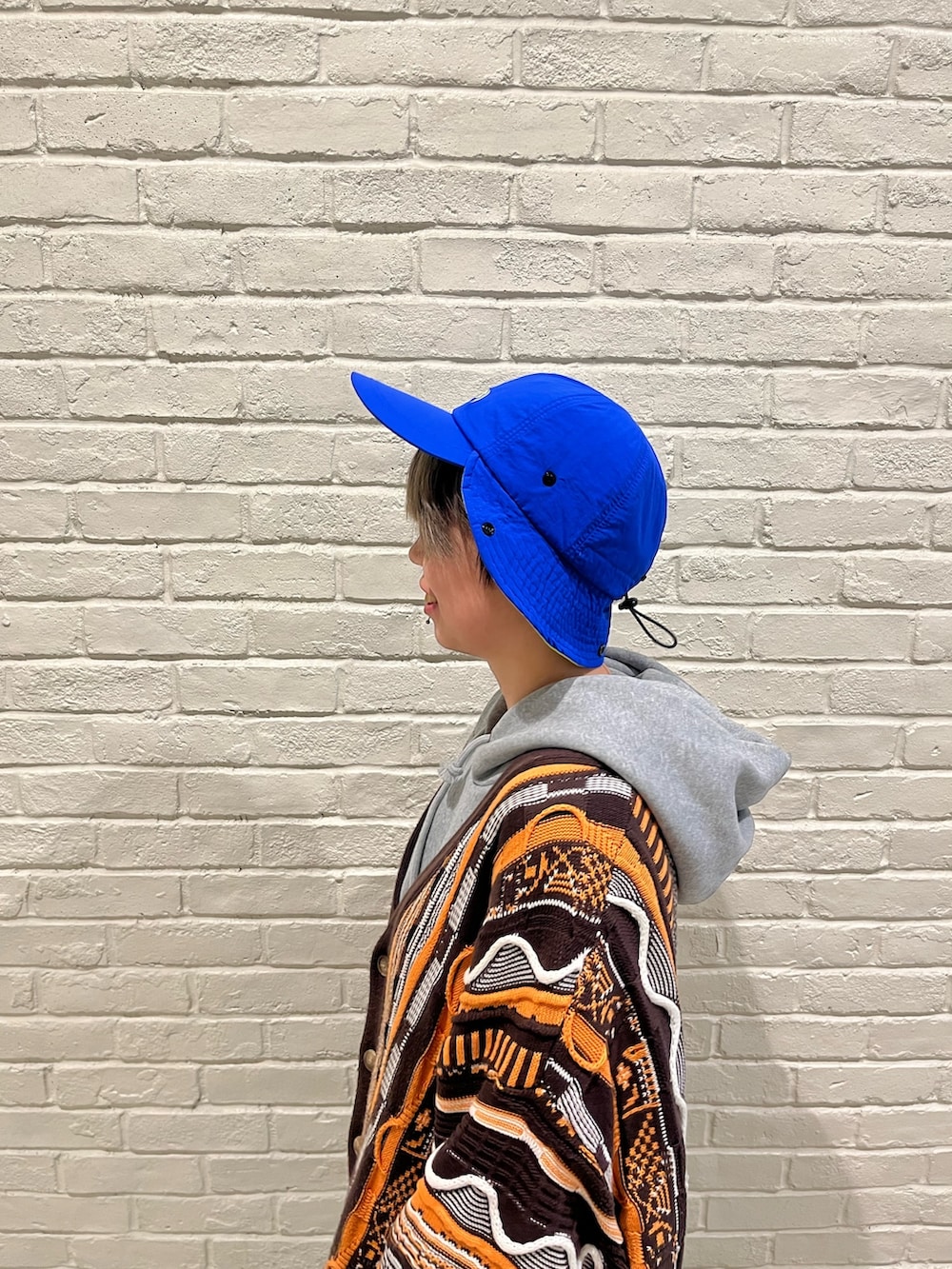 ベージュ系のパンツ、ブラック系のスニーカー、ブルー系のキャップを着用したレディースの春コーディネートの3枚目の写真