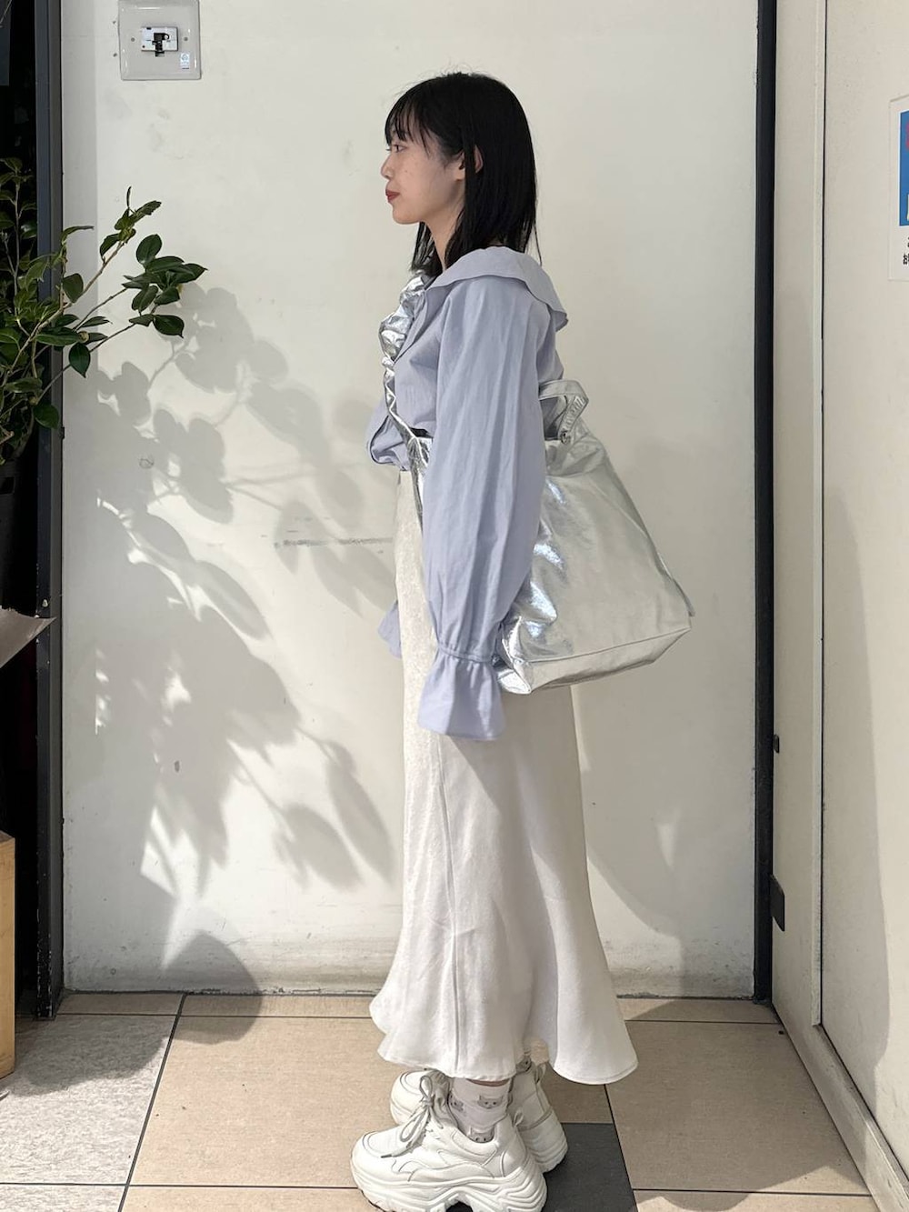 グレー系のトートバッグ、ブルー系のシャツ/ブラウス、ホワイト系のスカートを着用したレディースの冬コーディネートの2枚目の写真