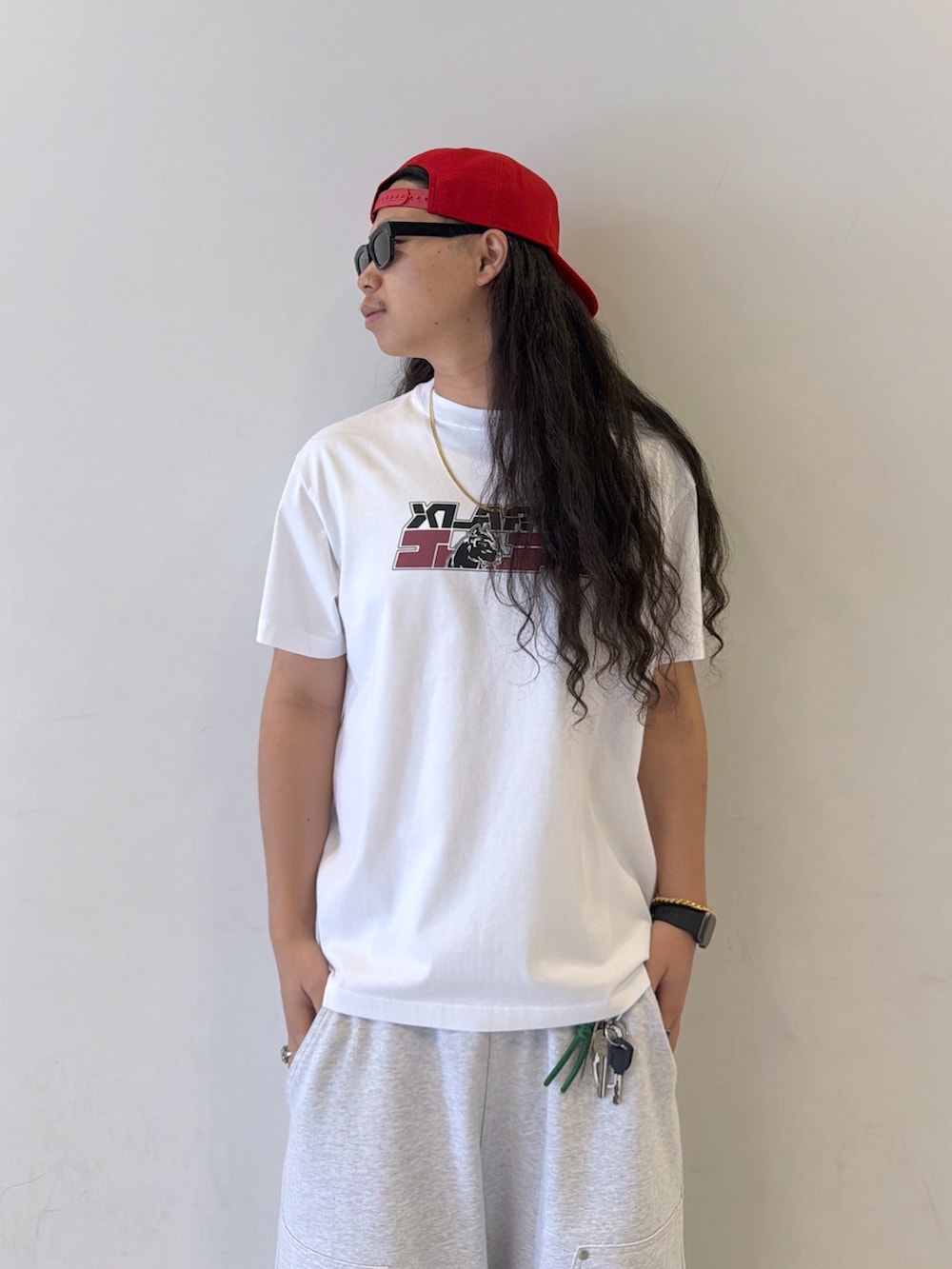 ホワイト系のTシャツ/カットソー、グレー系のスウェットパンツ、レッド系のキャップを着用したメンズの夏コーディネートの2枚目の写真