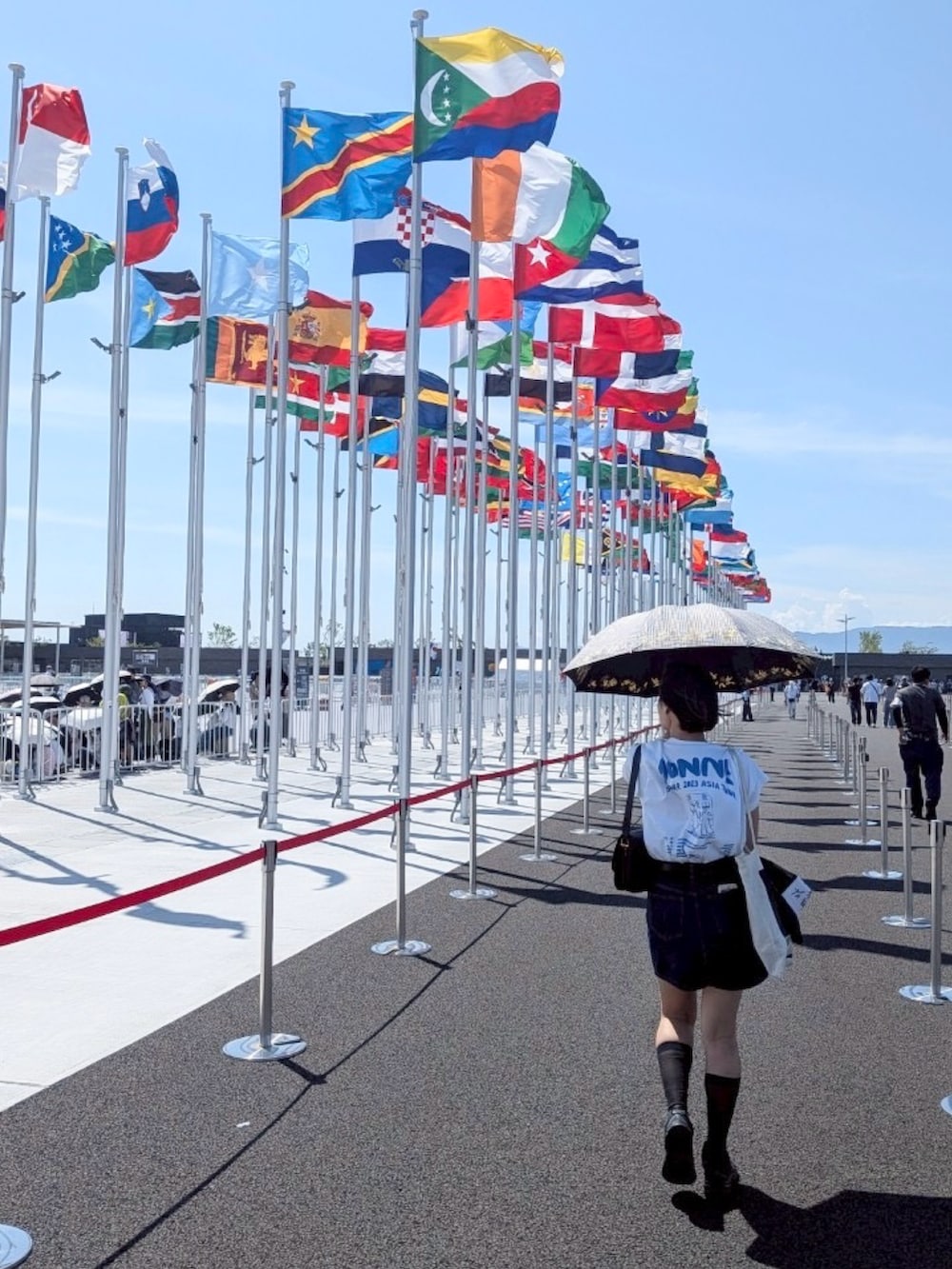 ブラック系のスニーカー、ホワイト系のTシャツ/カットソー、ブルー系のデニムスカートを着用したレディースの夏コーディネートの2枚目の写真