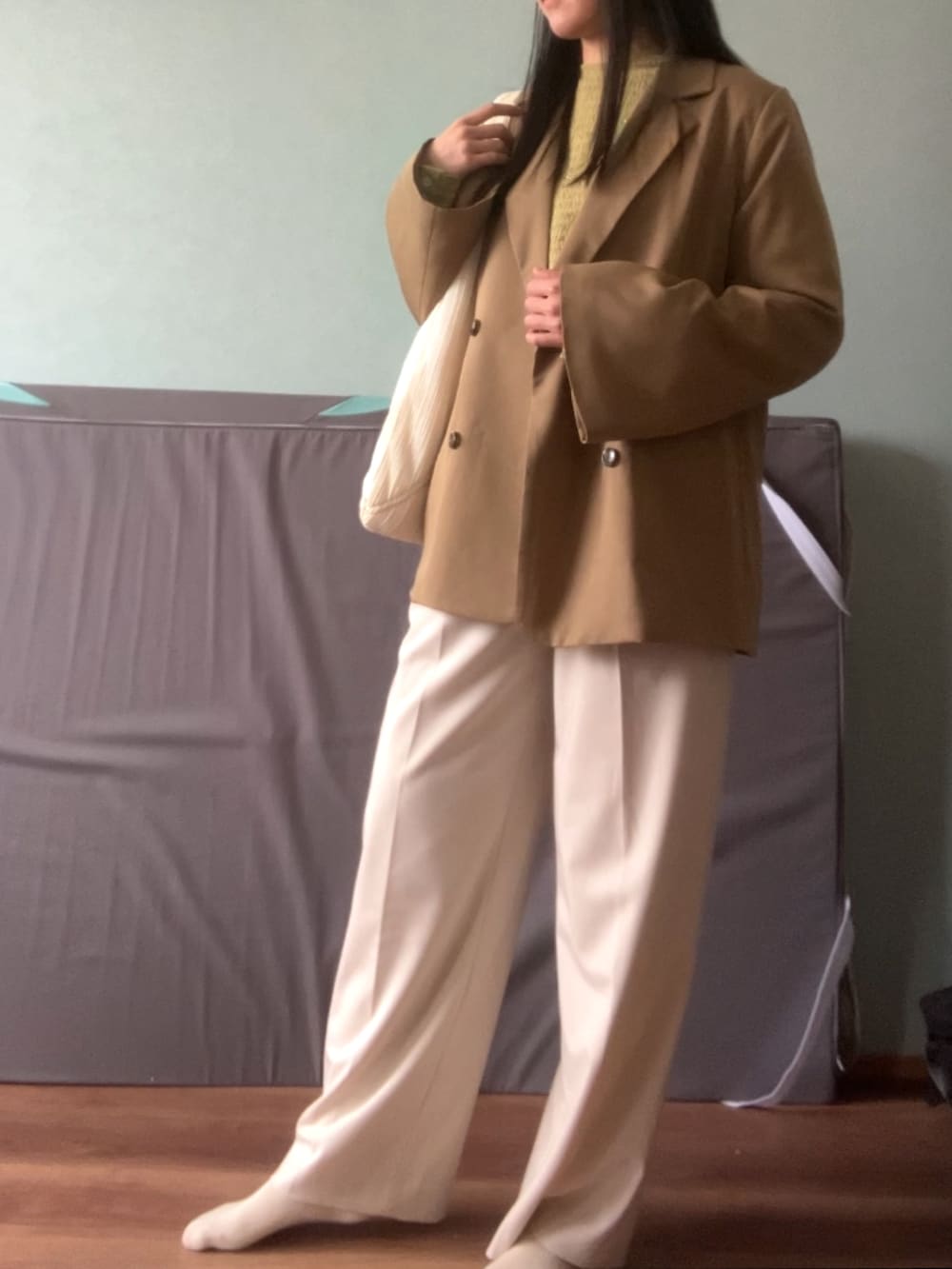 グリーン系のトップス、ベージュ系のテーラードジャケット、ホワイト系のスラックスを着用したレディースの春コーディネートの3枚目の写真