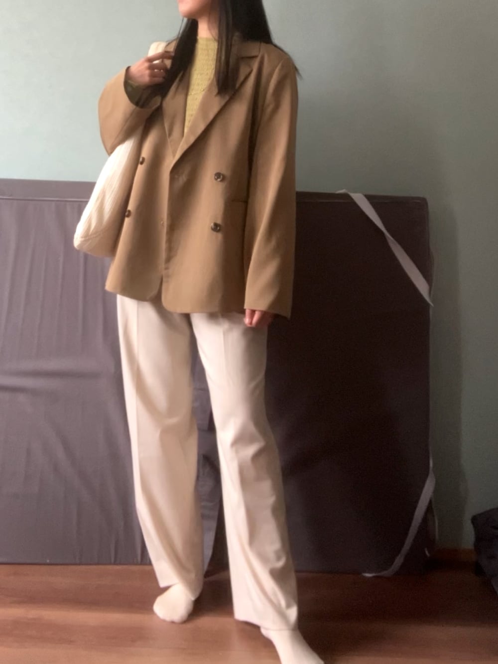 グリーン系のトップス、ベージュ系のテーラードジャケット、ホワイト系のスラックスを着用したレディースの春コーディネートの2枚目の写真