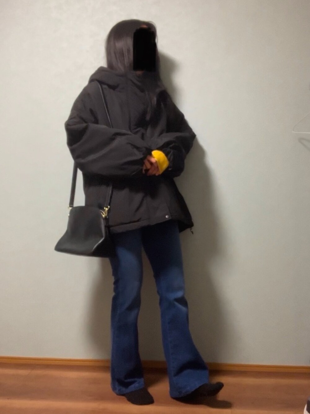 ブラック系のダウンジャケット/コート、イエロー系のニット/セーター、ホワイト系のTシャツ/カットソーを着用したレディースの冬コーディネートの2枚目の写真