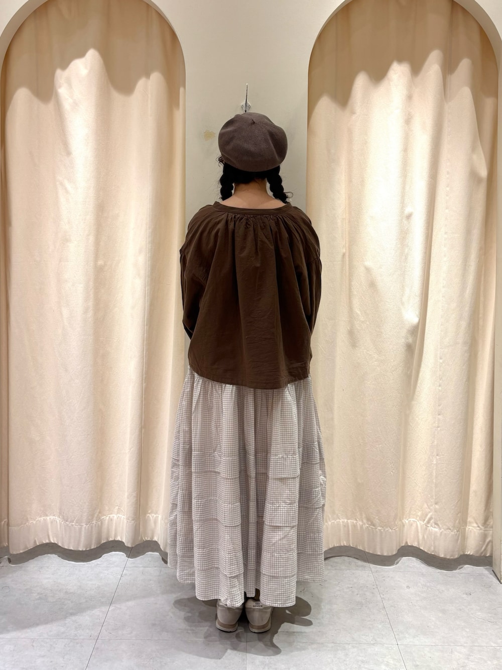 ブラウン系のノーカラージャケット、ベージュ系のスカート、ブラウン系のハットを着用したレディースの冬コーディネートの2枚目の写真