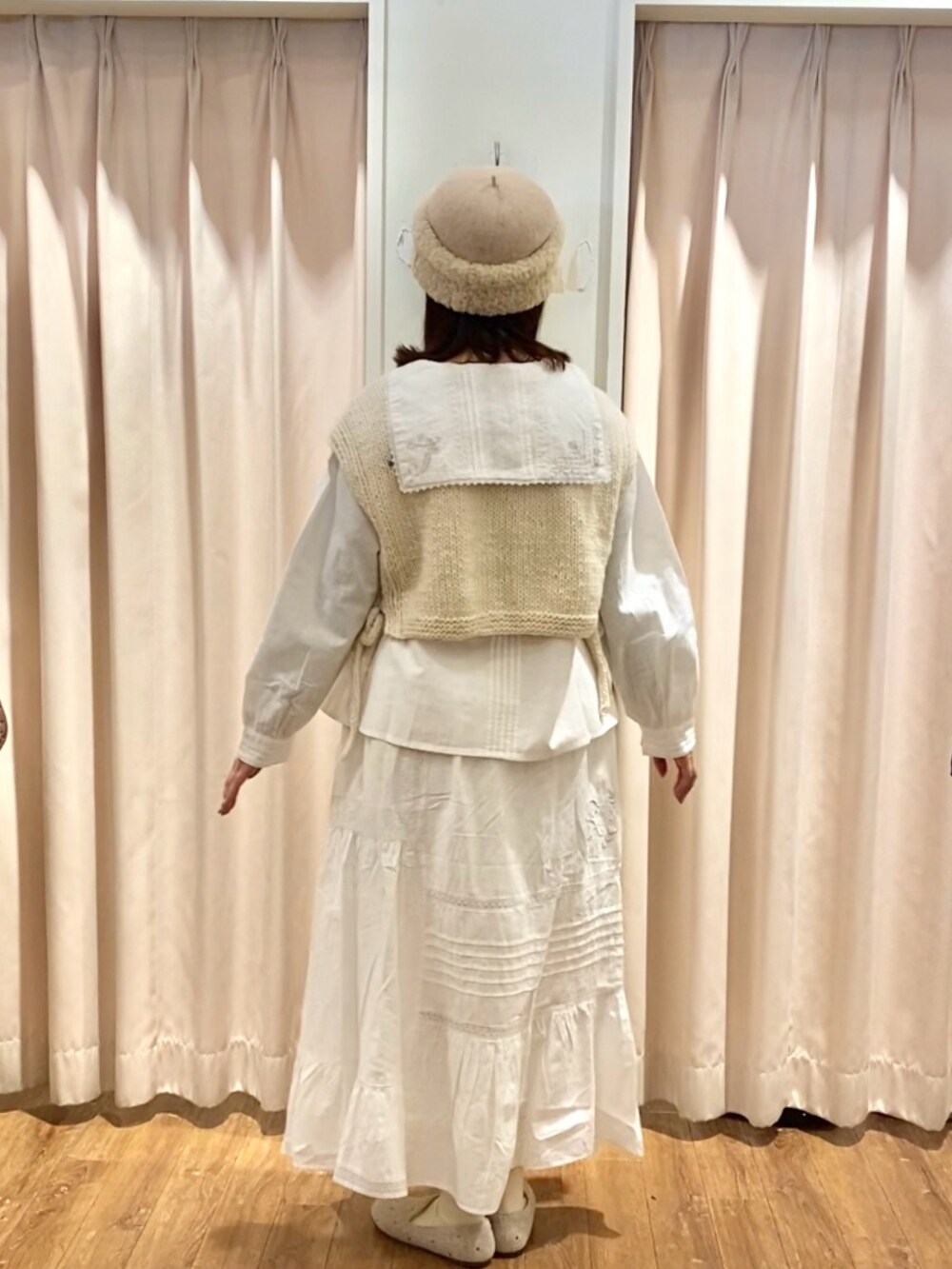 ホワイト系のベスト、ホワイト系のスカート、ベージュ系のドレスシューズを着用したレディースの秋コーディネートの2枚目の写真