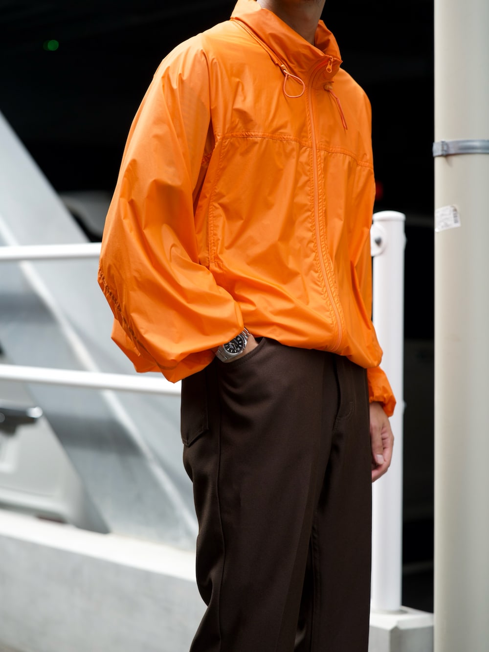 オレンジ系のダウンジャケット/コート、ブラウン系のスラックス、ホワイト系のスニーカーを着用したメンズの秋コーディネートの4枚目の写真