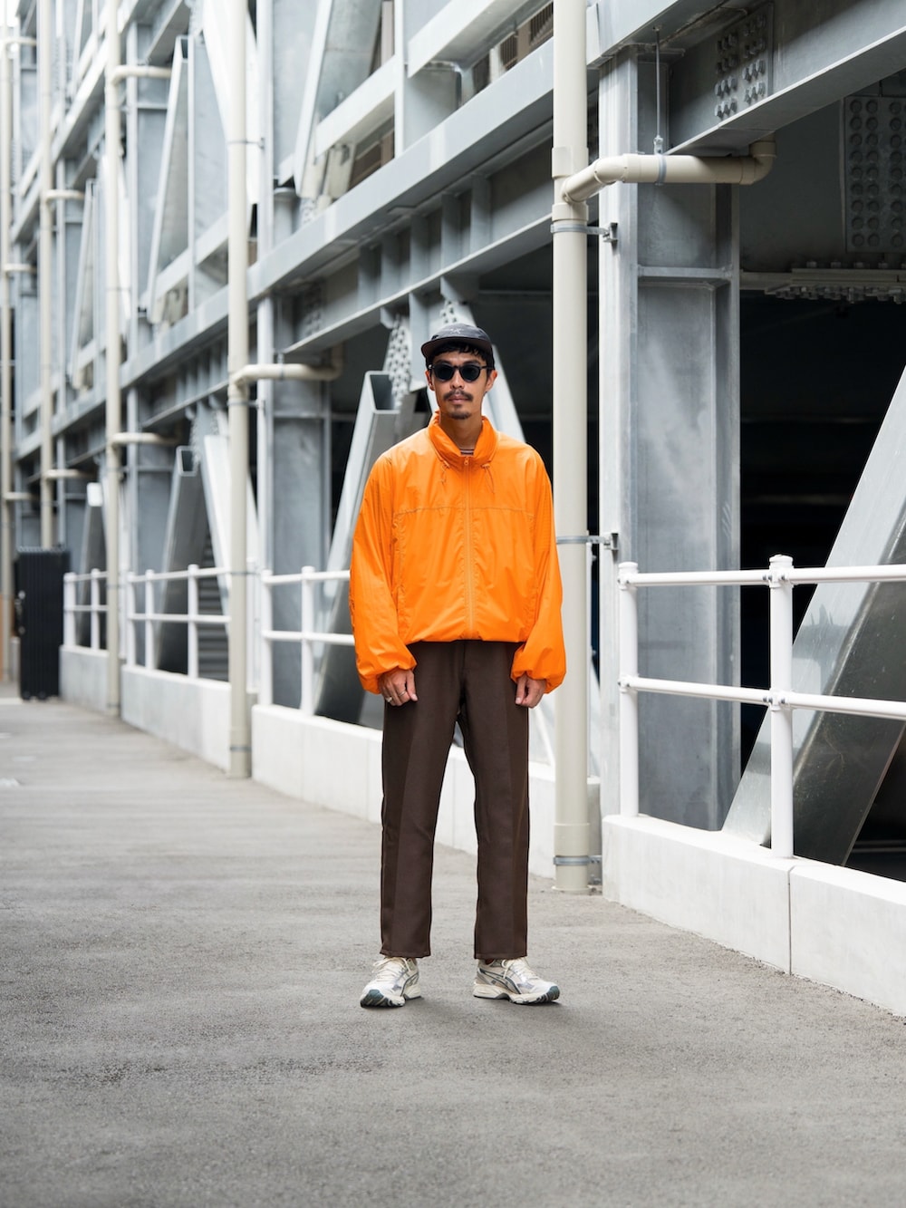 オレンジ系のダウンジャケット/コート、ブラウン系のスラックス、ホワイト系のスニーカーを着用したメンズの秋コーディネートの2枚目の写真