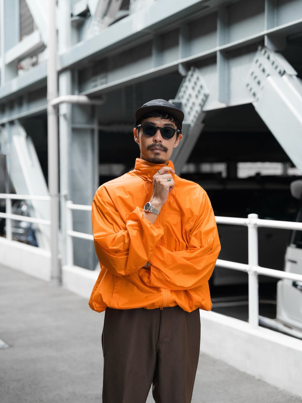 オレンジ系のダウンジャケット/コート、ブラウン系のスラックス、ホワイト系のスニーカーを着用したメンズの秋コーディネートの5枚目の写真