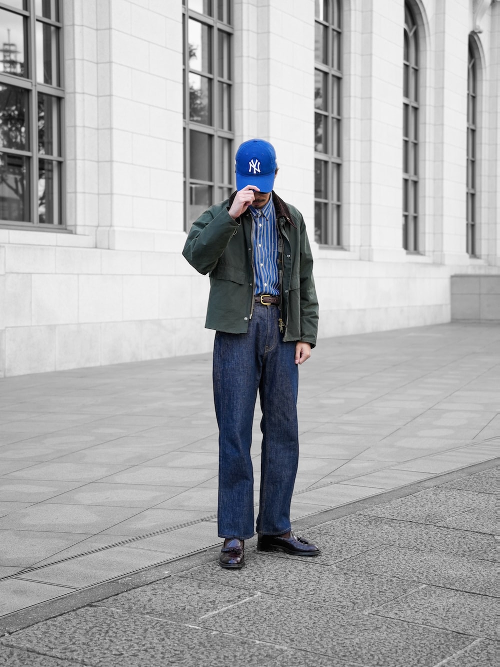 グリーン系のブルゾン、ブルー系のデニムパンツ、ブラウン系のドレスシューズを着用したメンズの春コーディネートの2枚目の写真