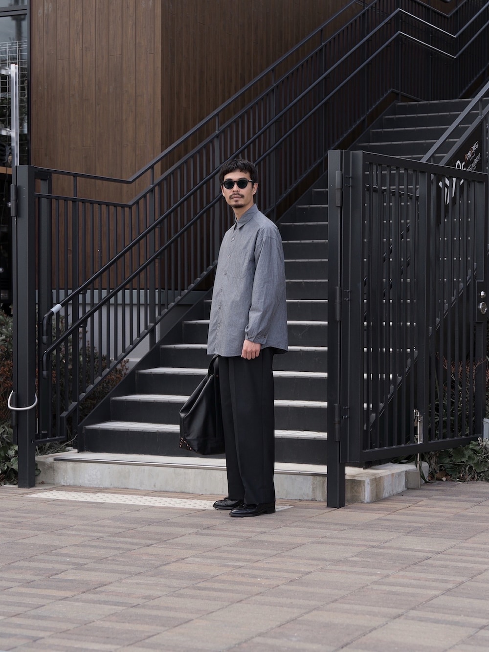 グレー系のシャツ/ブラウス、ブラック系のトートバッグ、ブラウン系のローファーを着用したメンズの春コーディネートの2枚目の写真