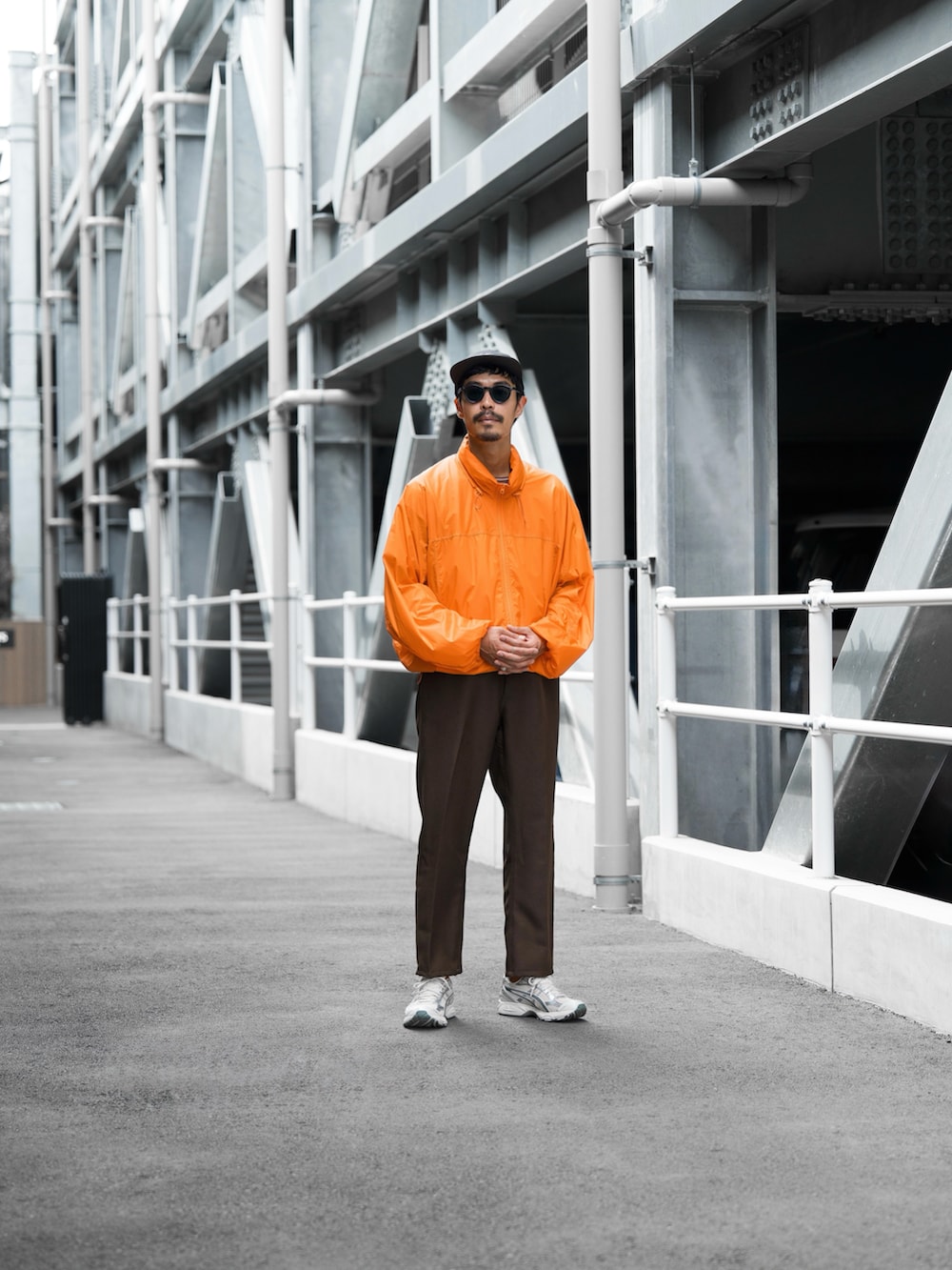 オレンジ系のダウンジャケット/コート、ブラウン系のスラックス、ホワイト系のスニーカーを着用したメンズの秋コーディネートの3枚目の写真