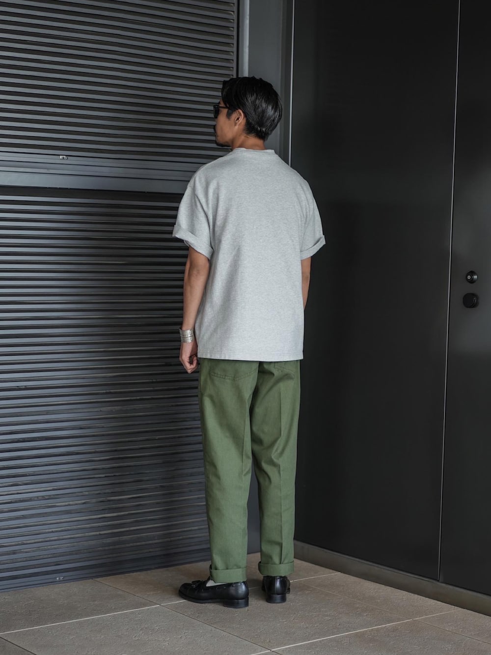 ホワイト系のTシャツ/カットソー、グリーン系のチノパンツ、ブラック系のローファーを着用したメンズの夏コーディネートの3枚目の写真