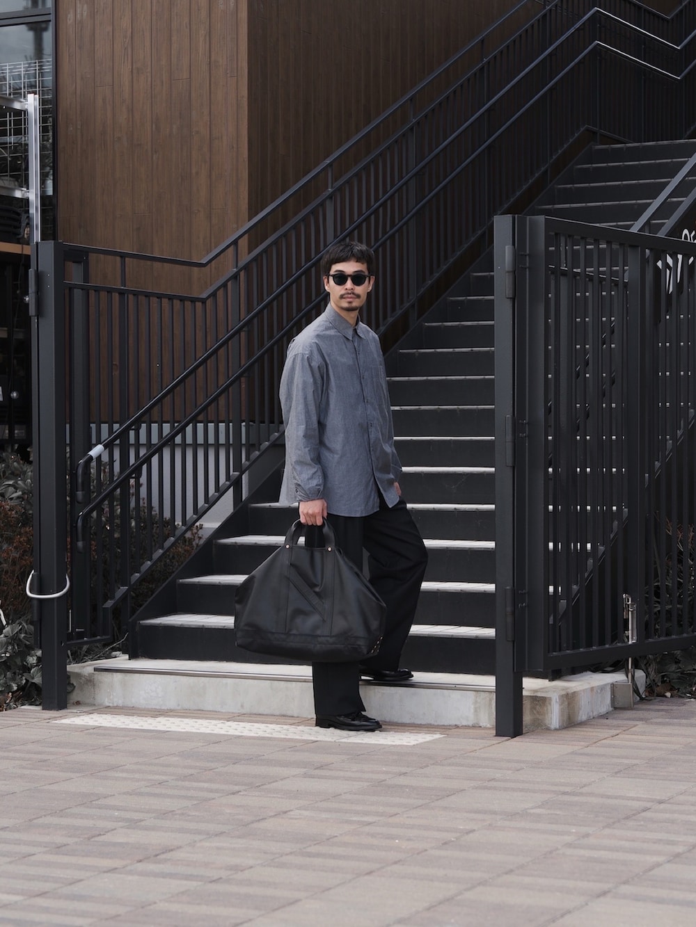 グレー系のシャツ/ブラウス、ブラック系のトートバッグ、ブラウン系のローファーを着用したメンズの春コーディネートの3枚目の写真