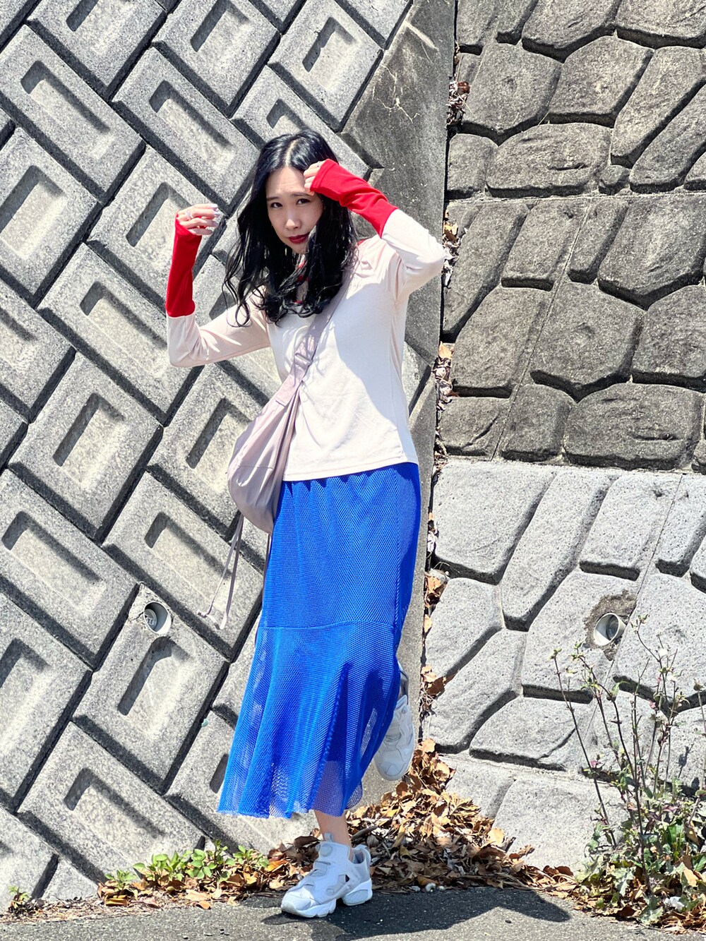 レッド系のTシャツ/カットソー、ブルー系のスカート、グレー系のスニーカーを着用したレディースの春コーディネートの2枚目の写真