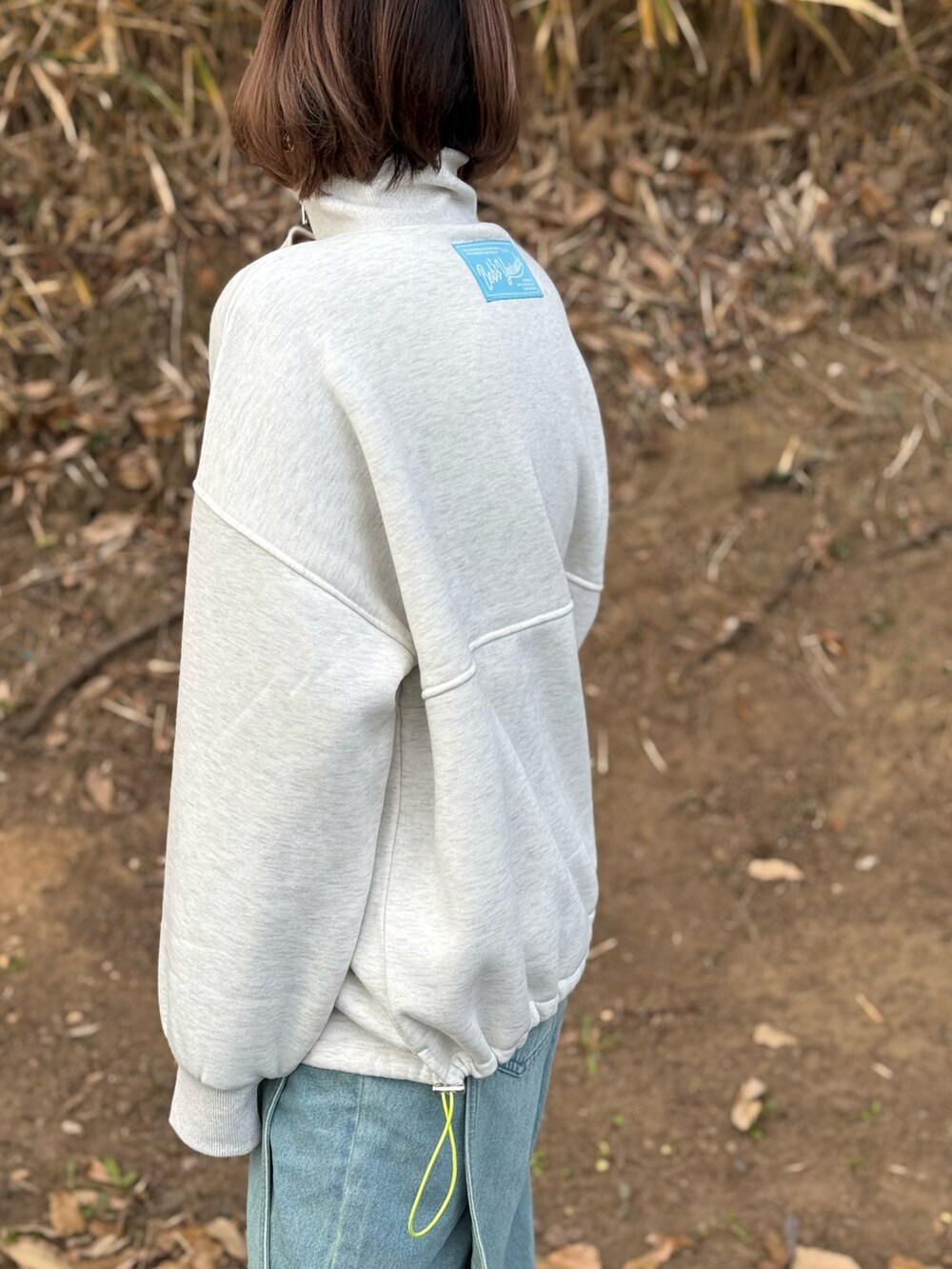 ベージュ系のスウェット、グレー系のTシャツ/カットソー、ブルー系のデニムパンツを着用したレディースの冬コーディネートの2枚目の写真