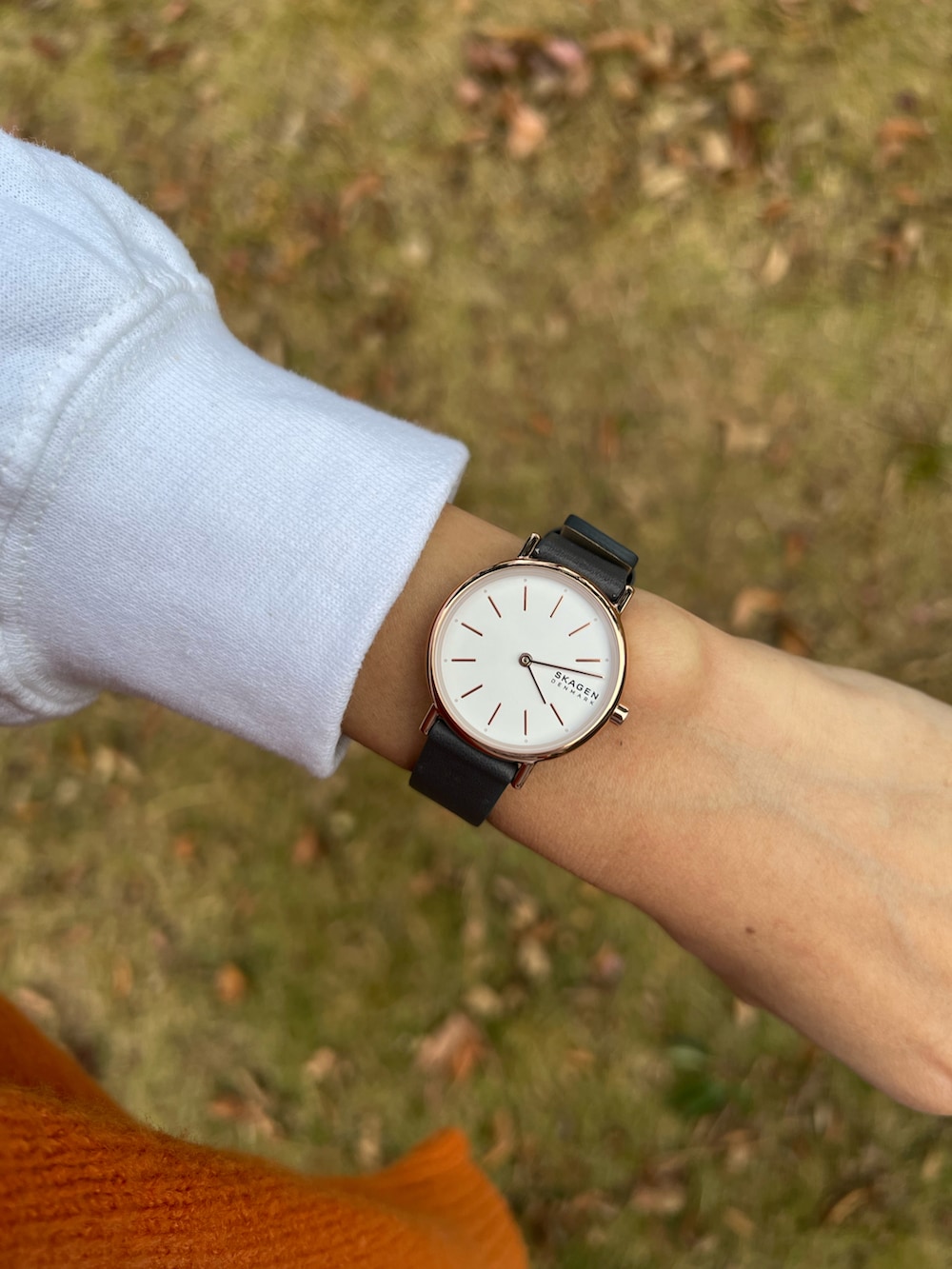 ホワイト系のスウェット、オレンジ系のカーディガン/ボレロ、ブラック系のスカートを着用したレディースの冬コーディネートの2枚目の写真