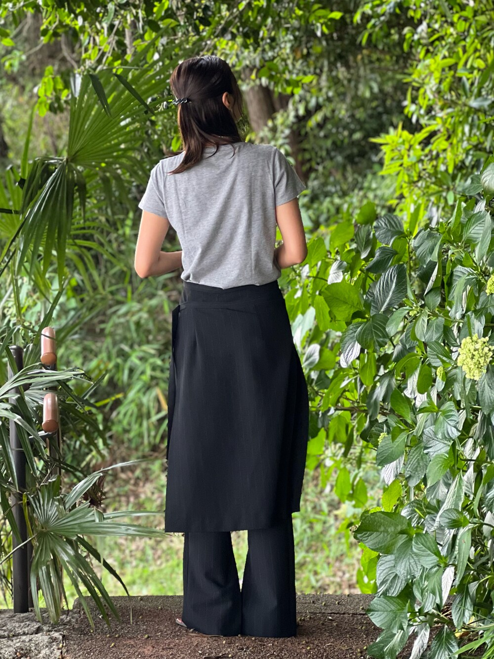 ブラック系のパンツ、ブラック系のバッグ、オレンジ系のサンダルを着用したレディースの春コーディネートの3枚目の写真