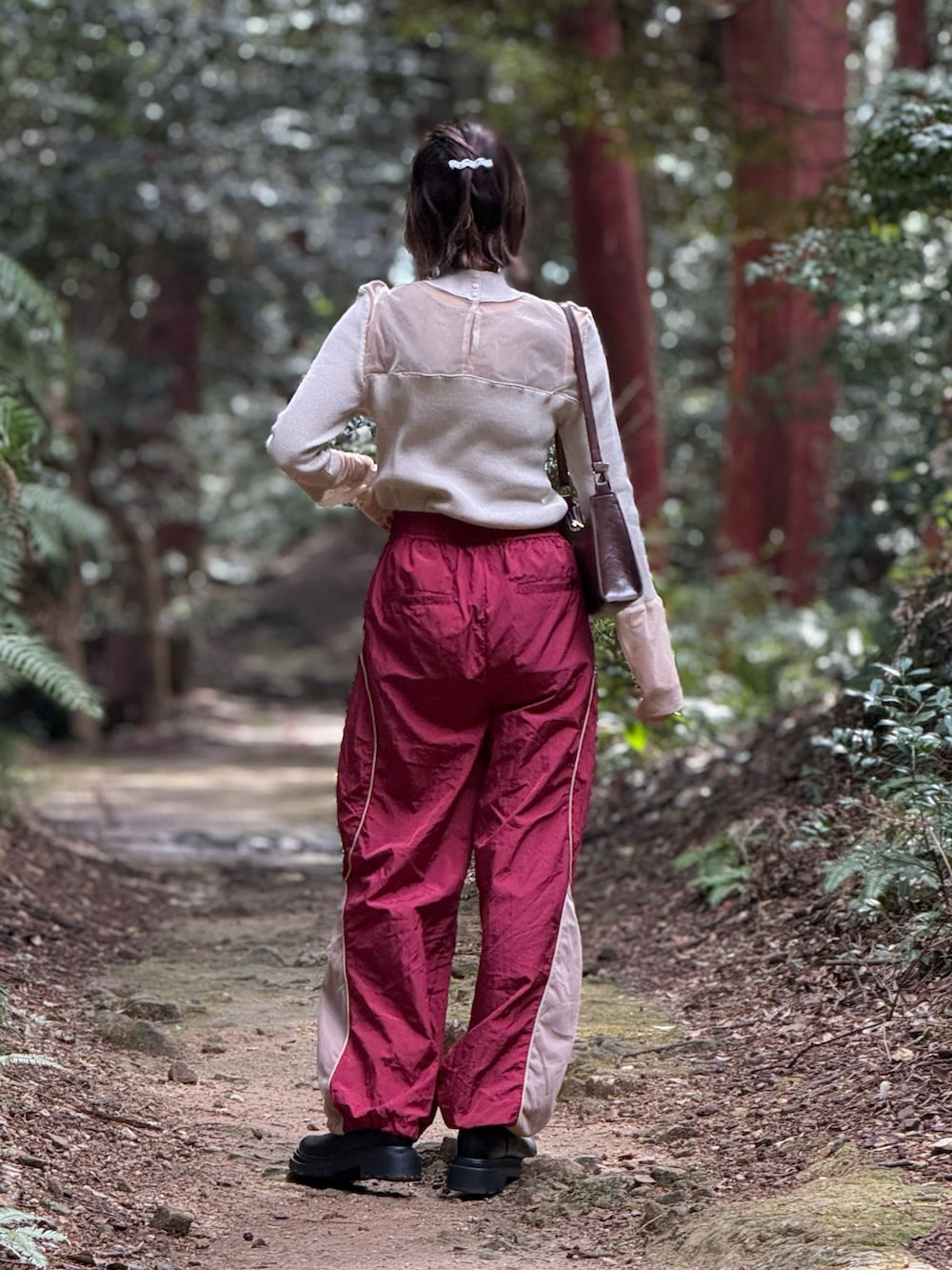 ブラウン系のショルダーバッグ、ベージュ系のニット/セーター、レッド系のその他パンツを着用したレディースの春コーディネートの2枚目の写真