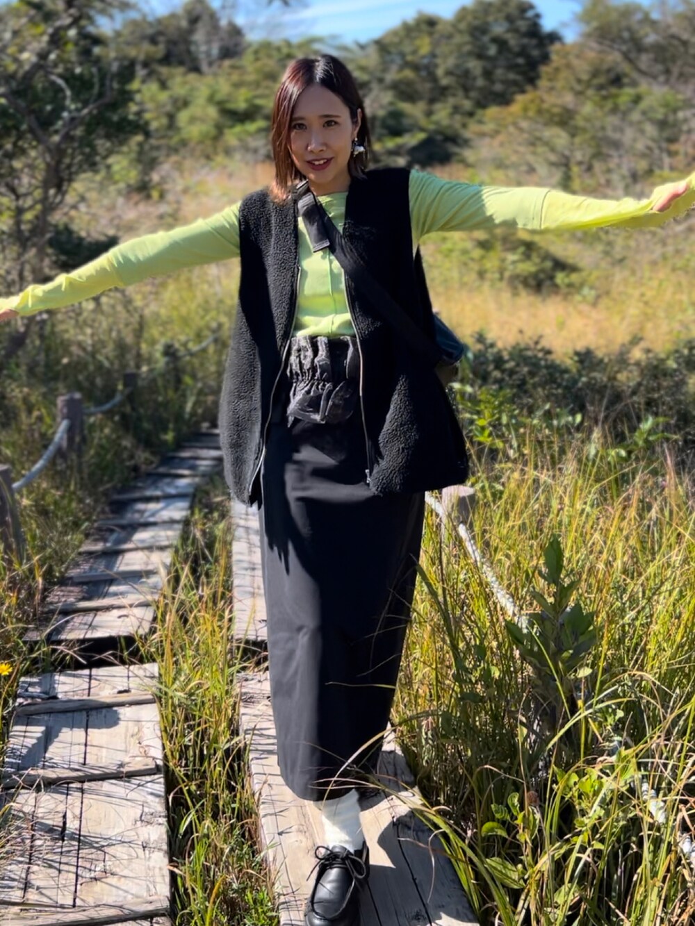 グリーン系のTシャツ/カットソー、ブラック系のベスト、ブラック系のスカートを着用したレディースの秋コーディネートの3枚目の写真