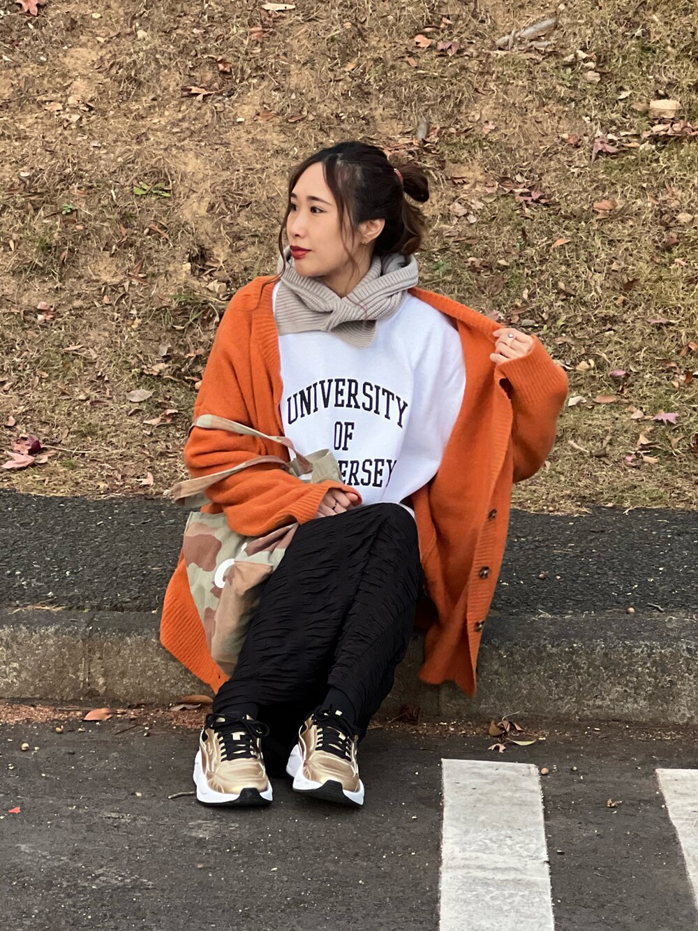 ホワイト系のスウェット、オレンジ系のカーディガン/ボレロ、ブラック系のスカートを着用したレディースの冬コーディネートの4枚目の写真