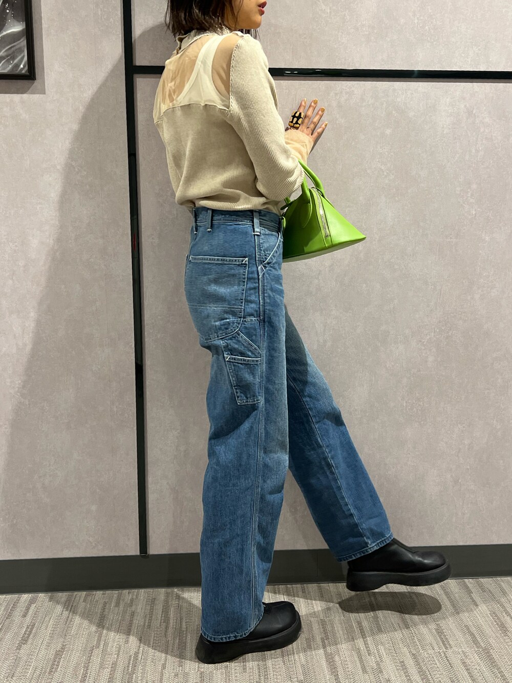 ブルー系のデニムパンツ、ホワイト系のタンクトップ、ベージュ系のニット/セーターを着用したレディースの秋コーディネートの3枚目の写真