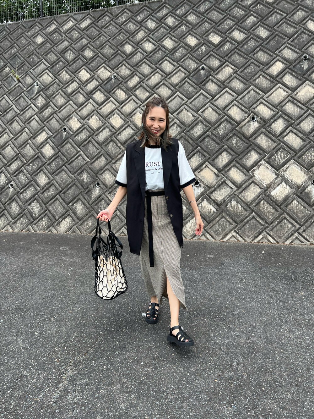ブラック系のTシャツ/カットソー、ベージュ系のスカート、ブラック系のサンダルを着用したレディースの夏コーディネートの4枚目の写真