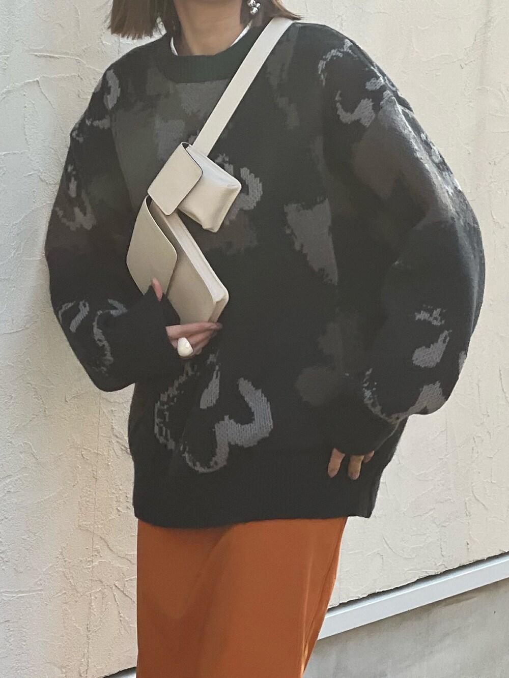 ブラック系のニット/セーター、イエロー系のスカート、ブラック系のブーツを着用したレディースの秋コーディネートの5枚目の写真