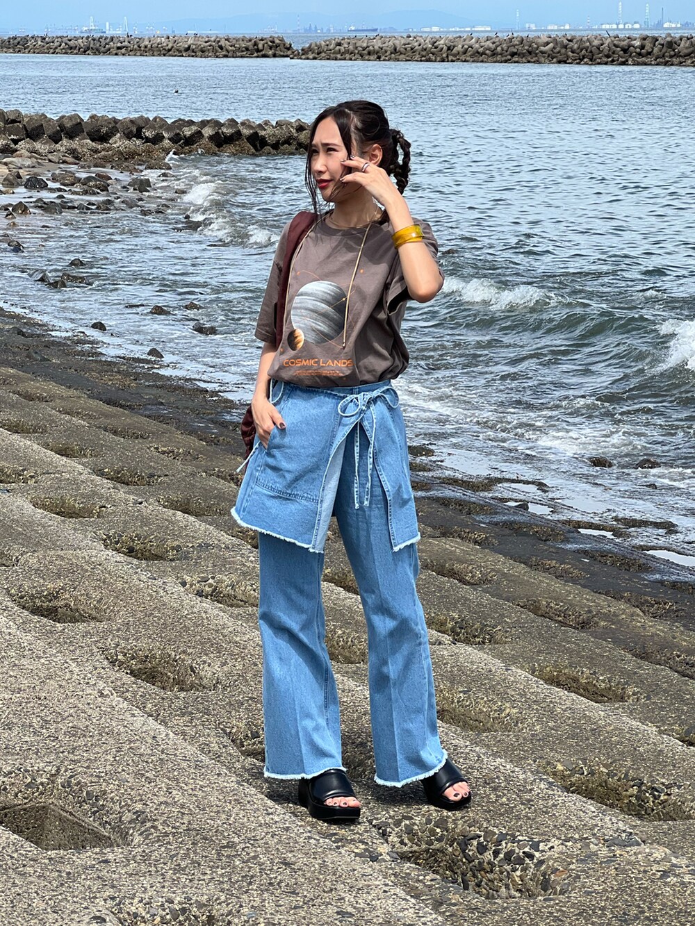 ブルー系のデニムパンツ、ブラウン系のTシャツ/カットソー、ブラック系のサンダルを着用したレディースの夏コーディネートの5枚目の写真