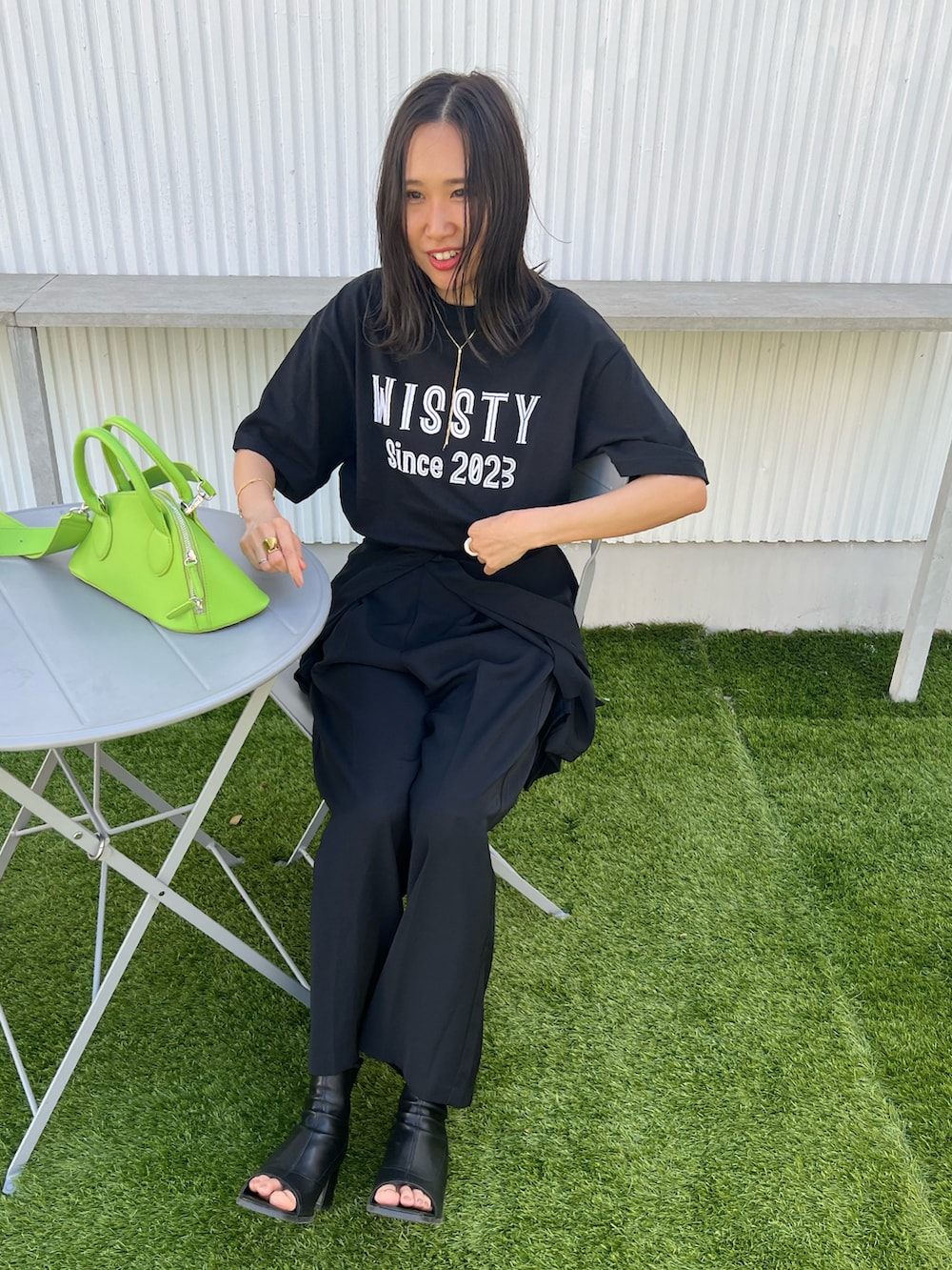 ブラック系のTシャツ/カットソー、ブラック系のブーツ、グリーン系のボストンバッグを着用したレディースの春コーディネートの4枚目の写真