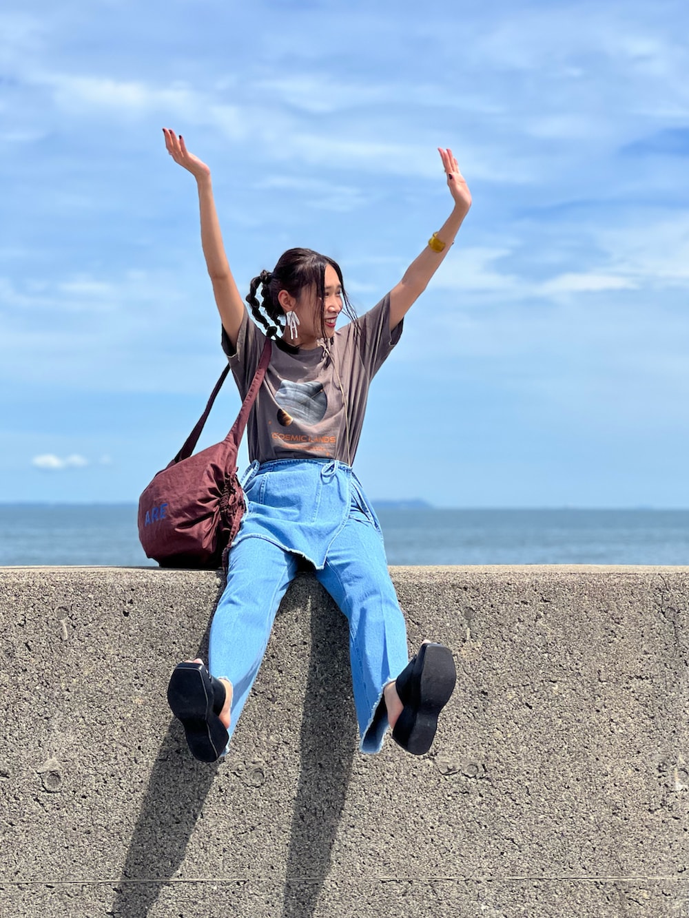 ブルー系のデニムパンツ、ブラウン系のTシャツ/カットソー、ブラック系のサンダルを着用したレディースの夏コーディネートの2枚目の写真