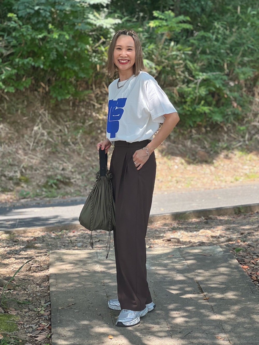 シルバー系のスニーカー、ホワイト系のTシャツ/カットソー、ブラウン系のパンツを着用したレディースの夏コーディネートの3枚目の写真