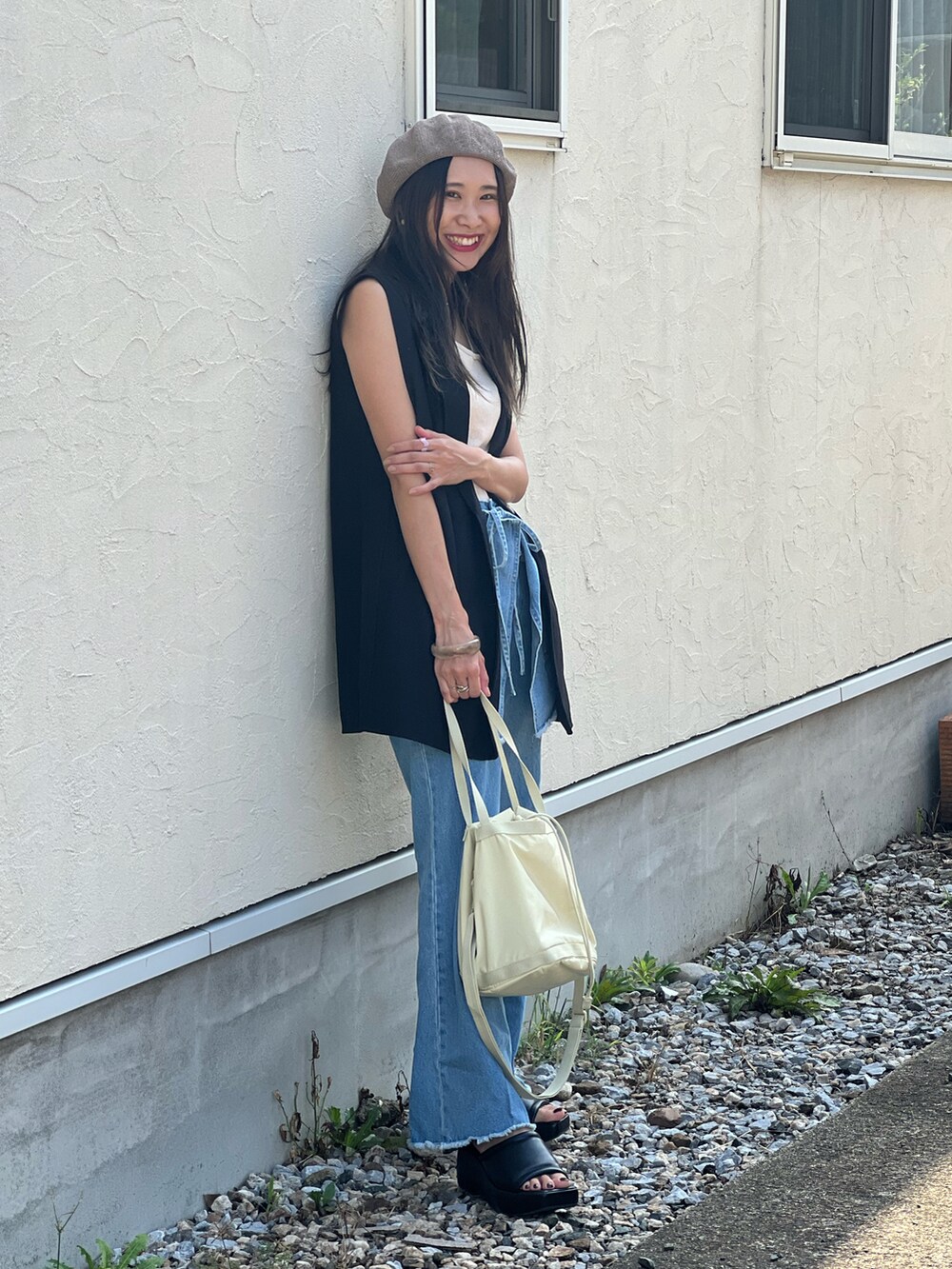ブルー系のデニムパンツ、ベージュ系のショルダーバッグ、ブラック系のサンダルを着用したレディースの夏コーディネートの4枚目の写真