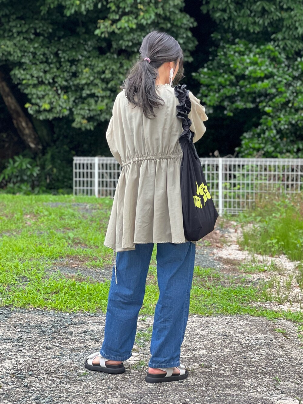 ブルー系のサロペット/オーバーオール、ブラック系のトートバッグ、ホワイト系のサンダルを着用したレディースの夏コーディネートの3枚目の写真