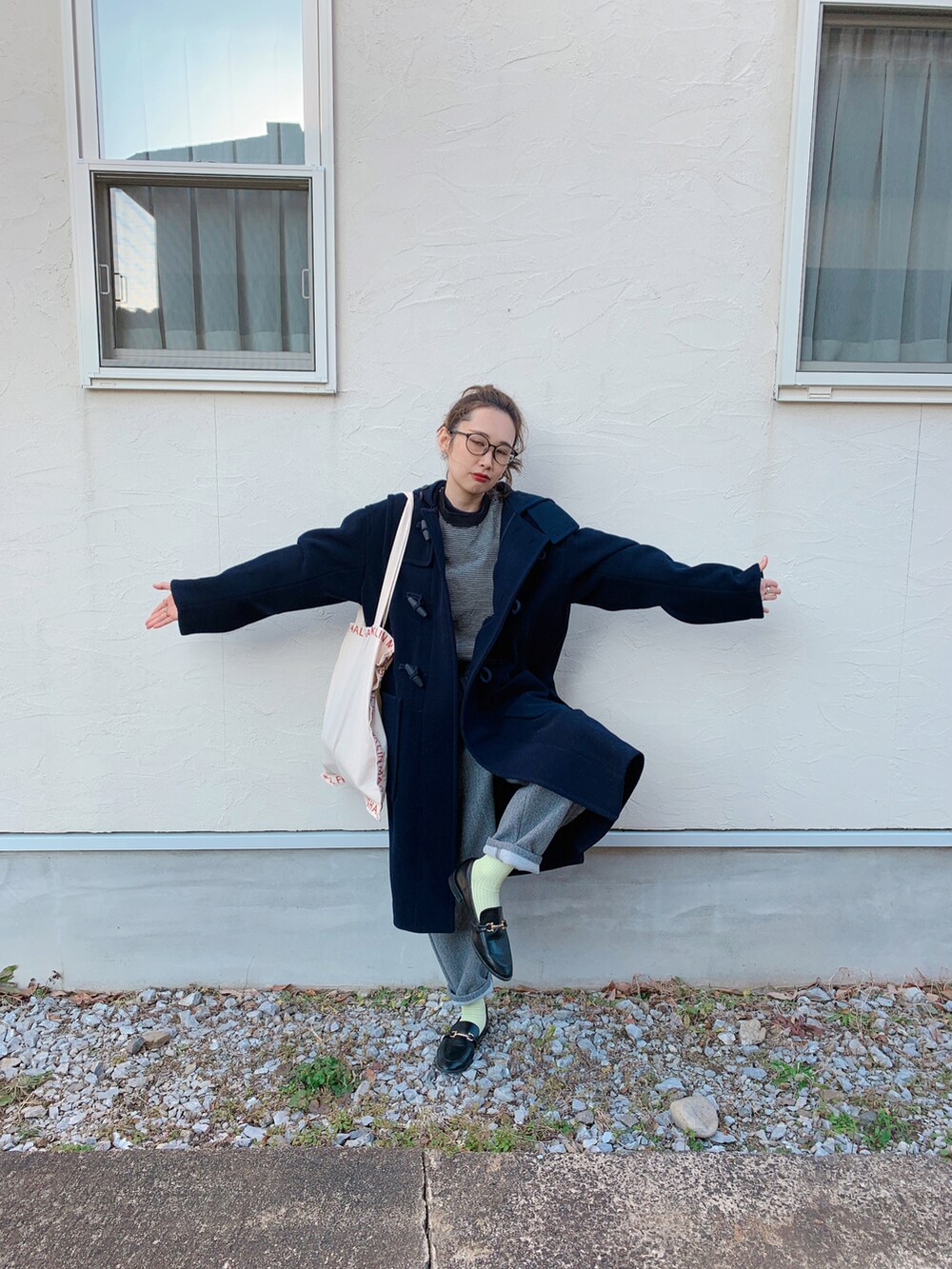 ブラック系のダッフルコート、ブラック系のローファー、レッド系のトートバッグを着用したレディースの冬コーディネートの5枚目の写真